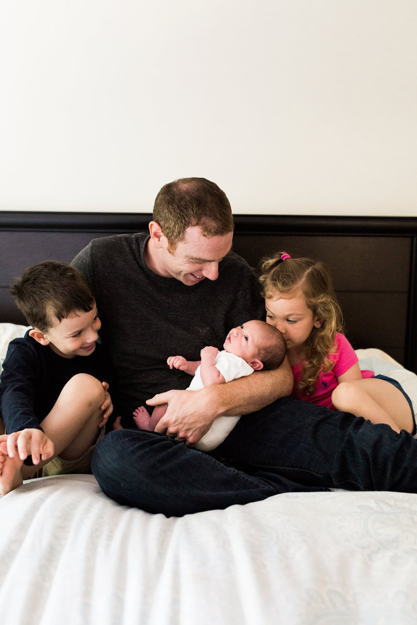 photo of newborn and siblings with dad in home