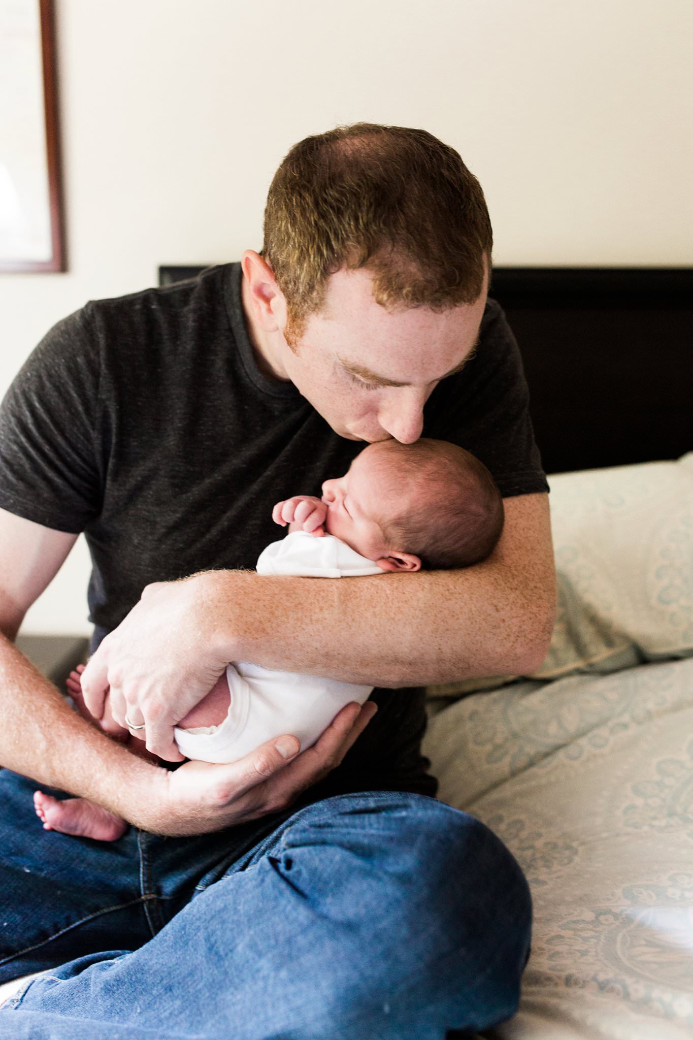 dad kissing newborn baby at home