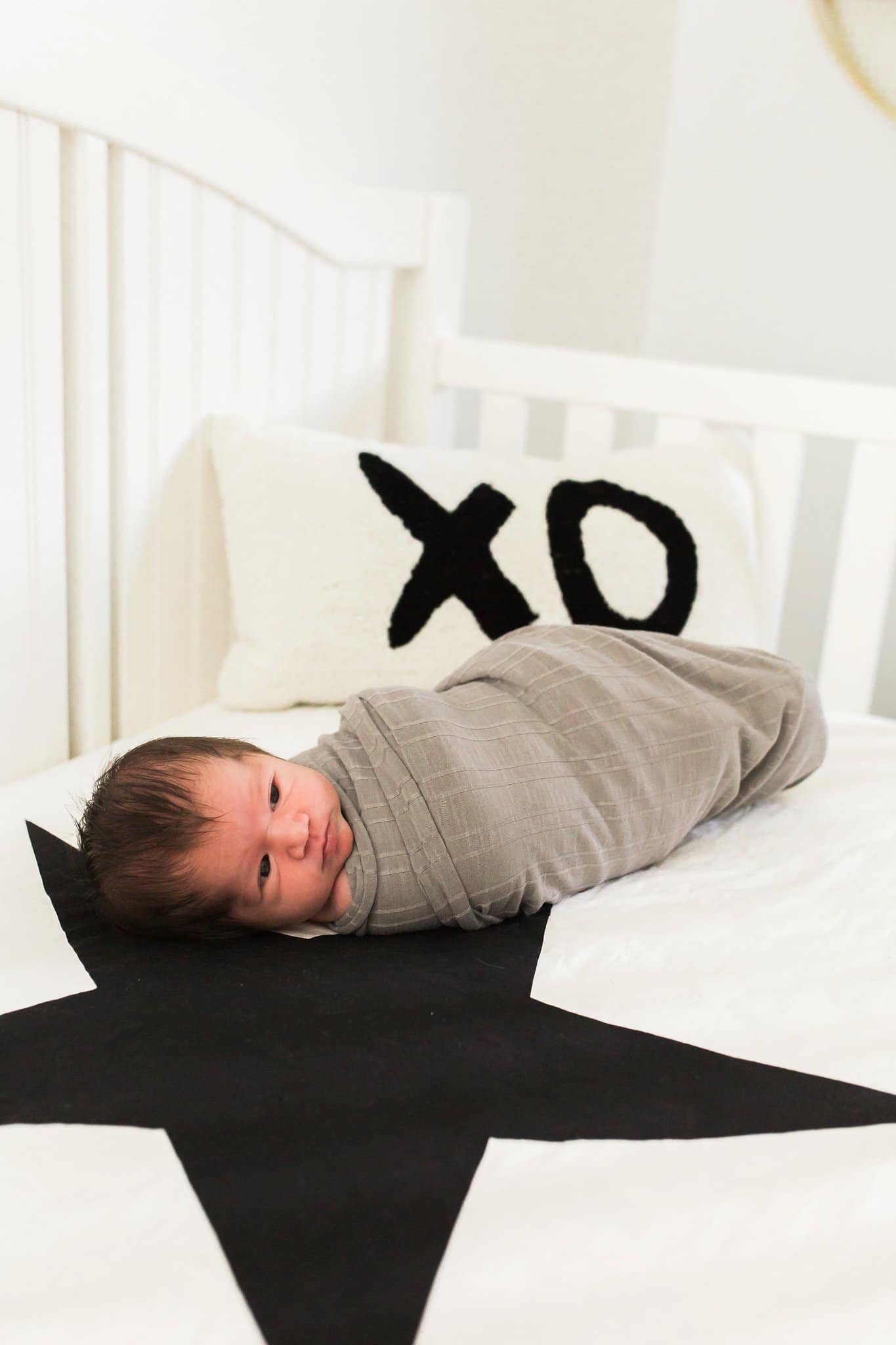 Newborn in crib with pottery barn pillows