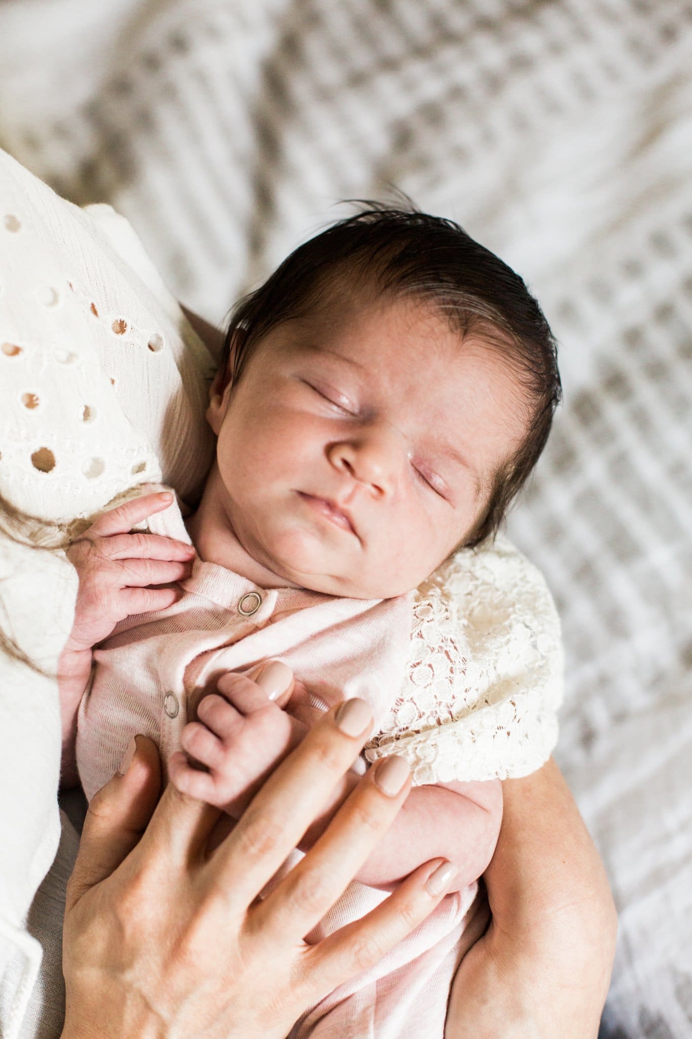 mother holding newborn on bed in home