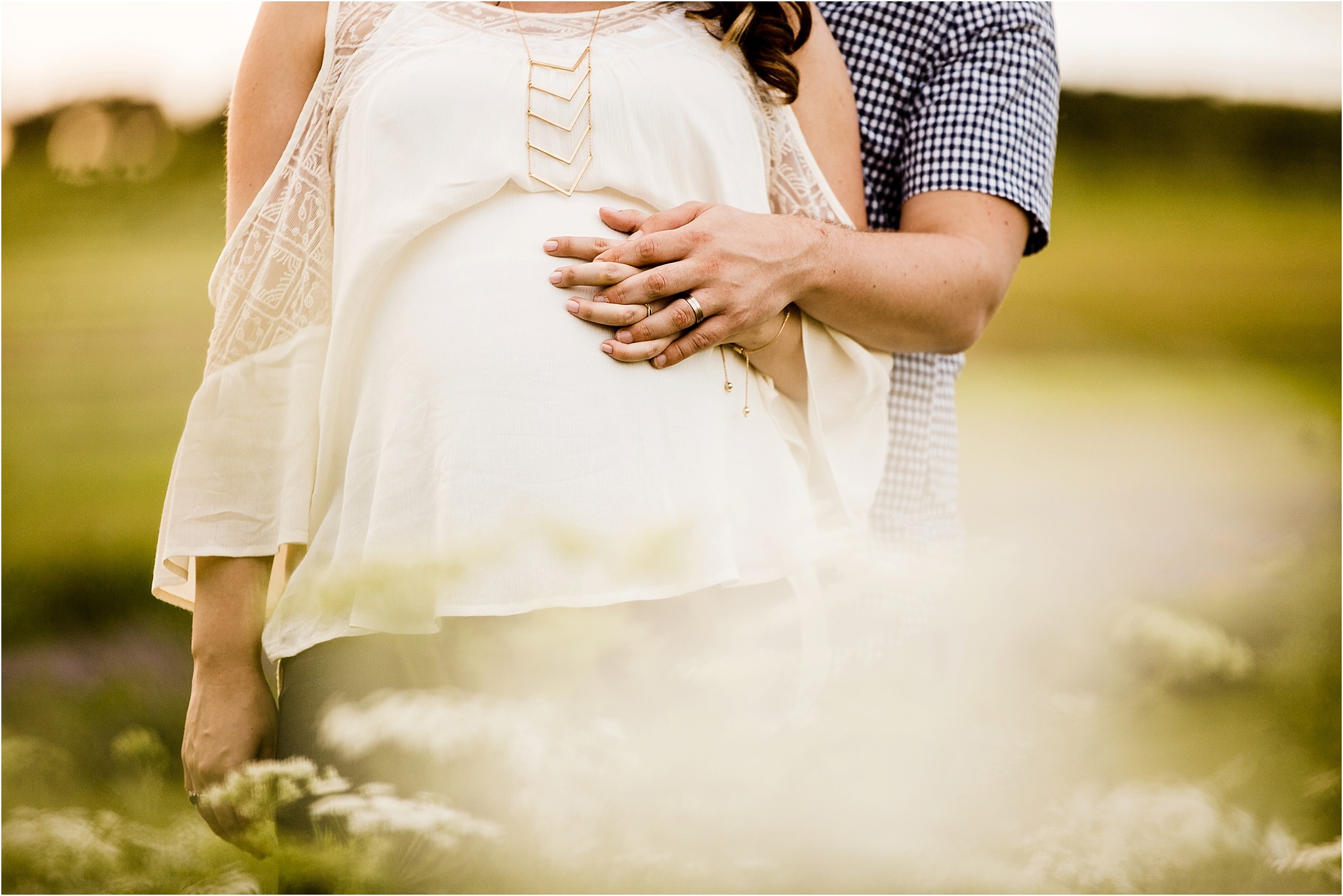 husband and wife hold hands with baby bump