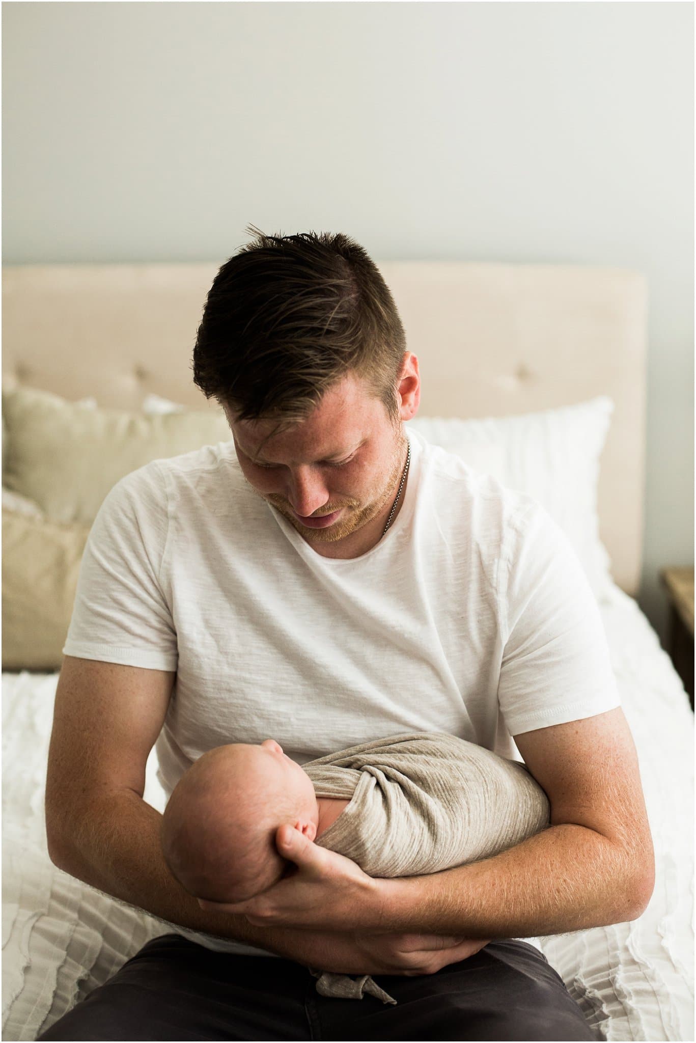 father holding newborn son in bedroom of home