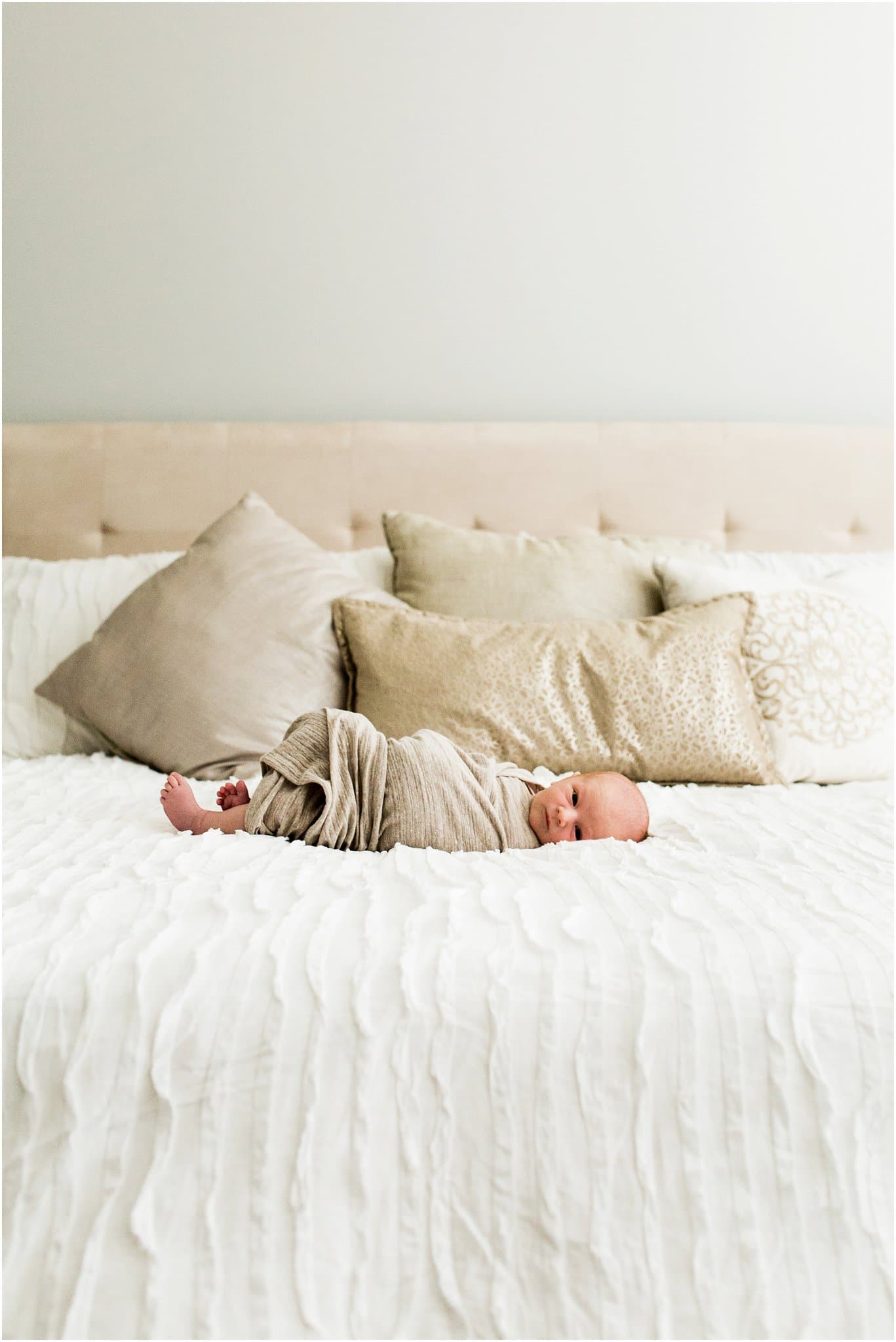 newborn boy swaddled on bed