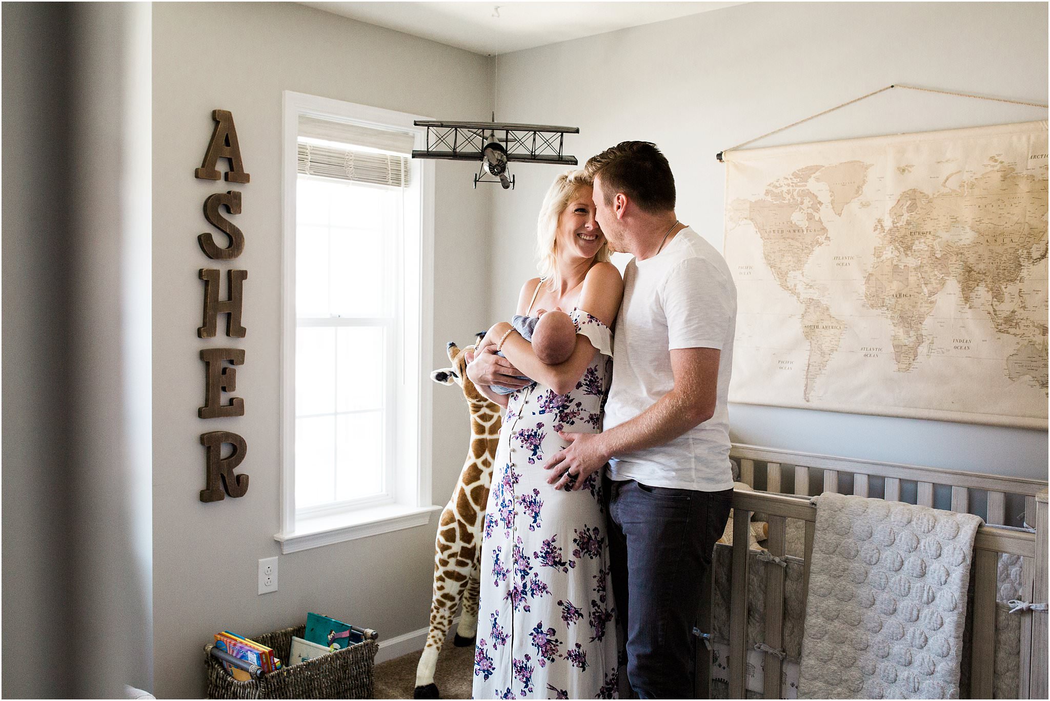 mother and father looking to newborn baby boy in travel inspired home nursery