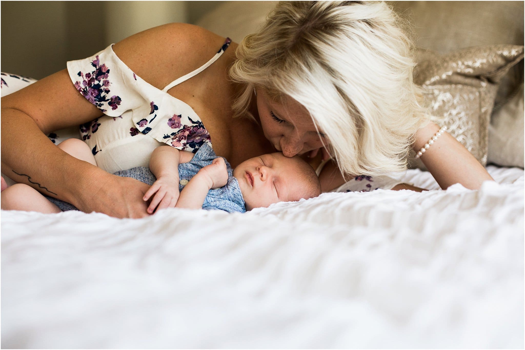 beautiful mother kissing newborn on bed of pittsburgh home