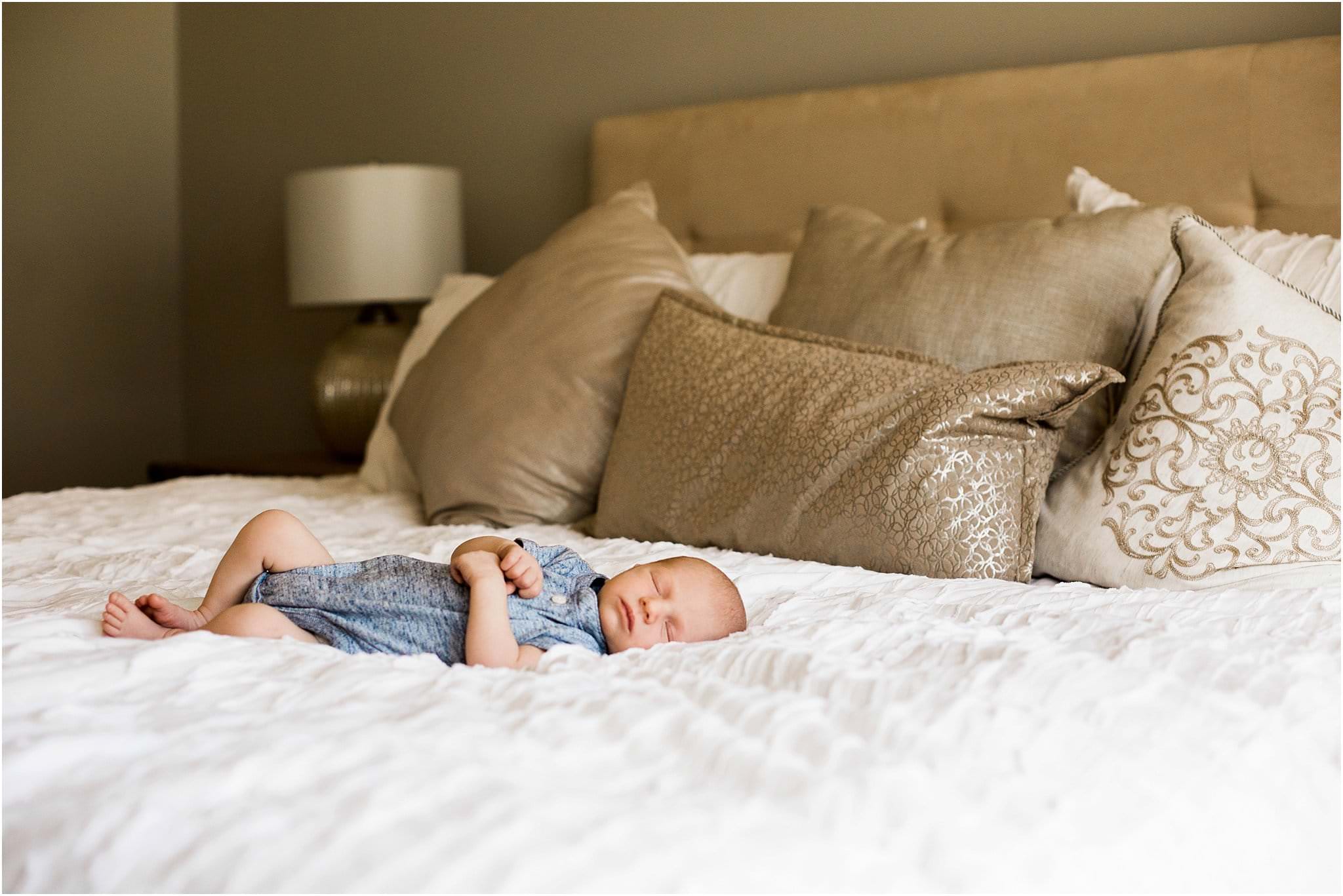 newborn baby stretched out and sleeping on bed