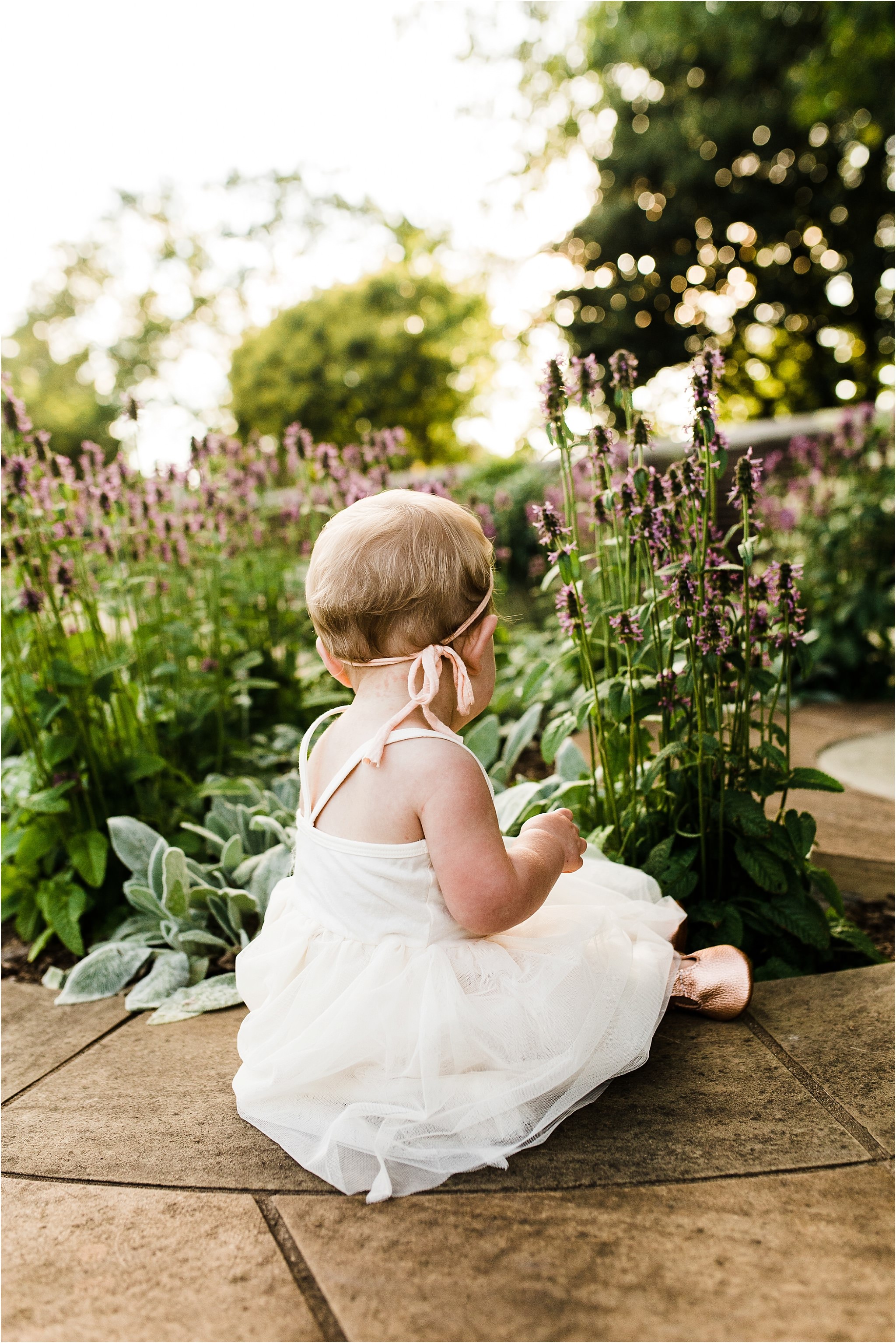 one year old baby girl picking flowers