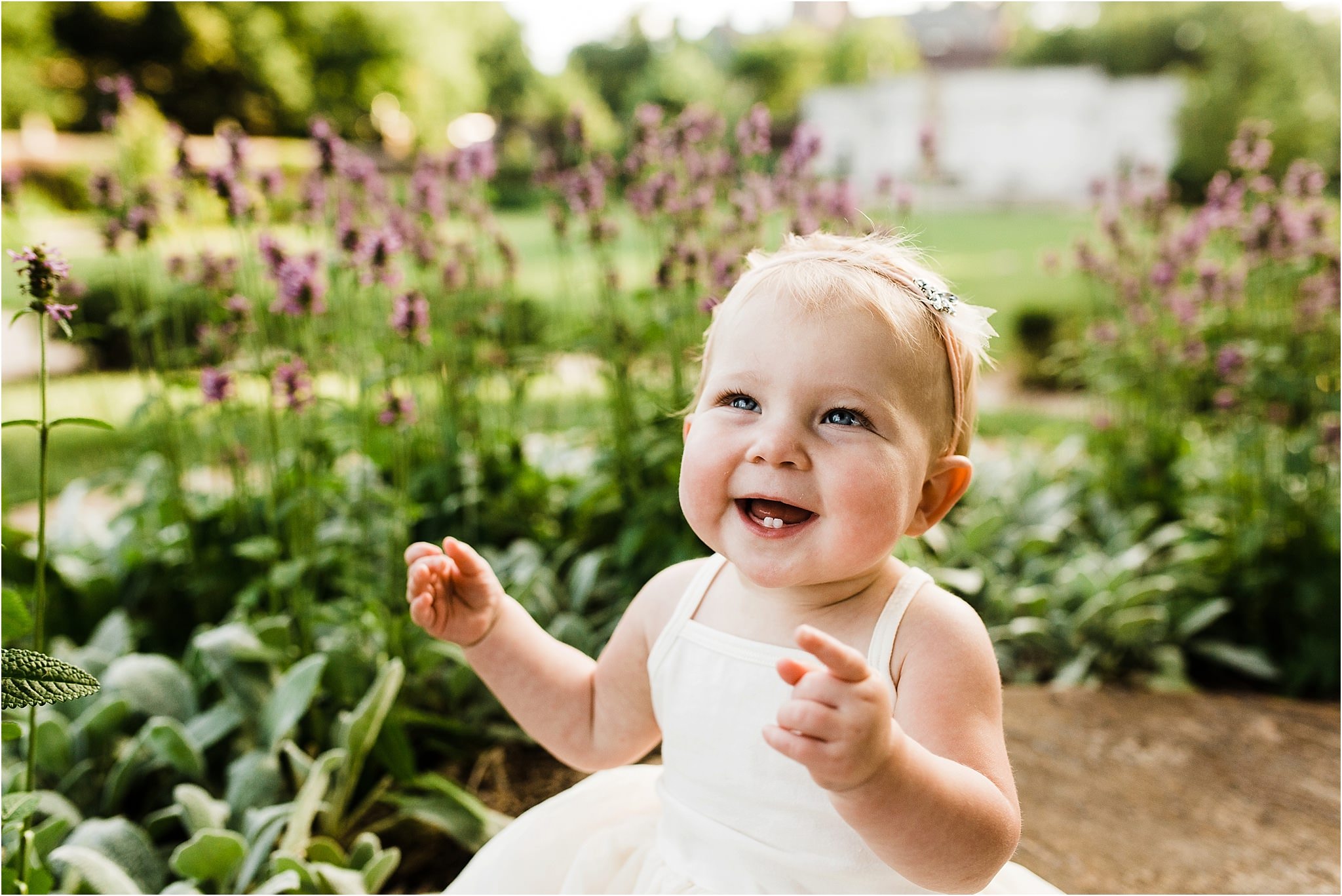 one year old baby girl smiling in flowers