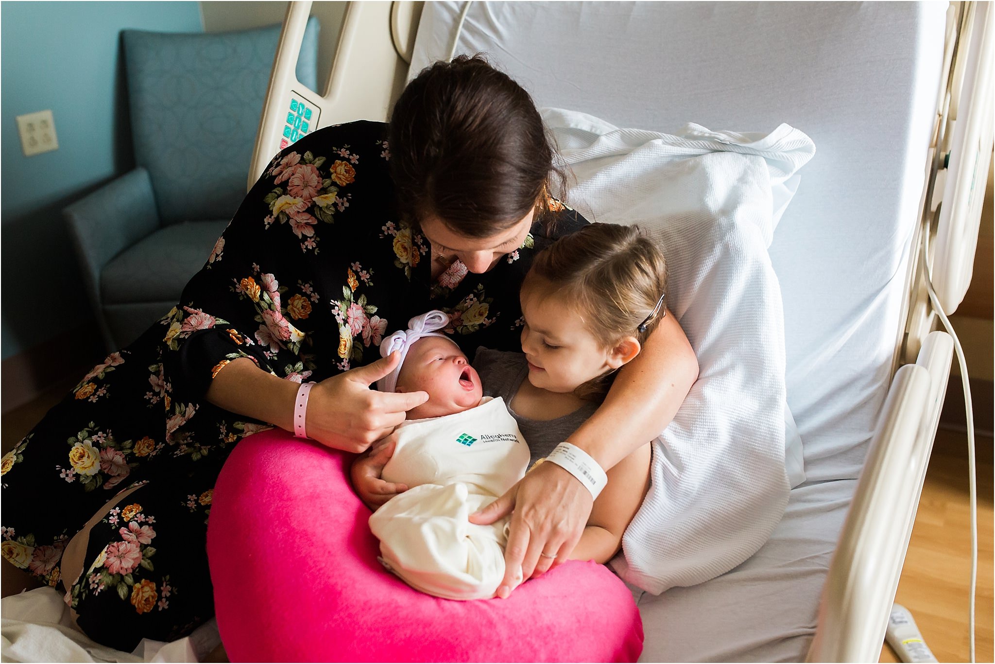 mother holding daughter with newborn daughter at hospital