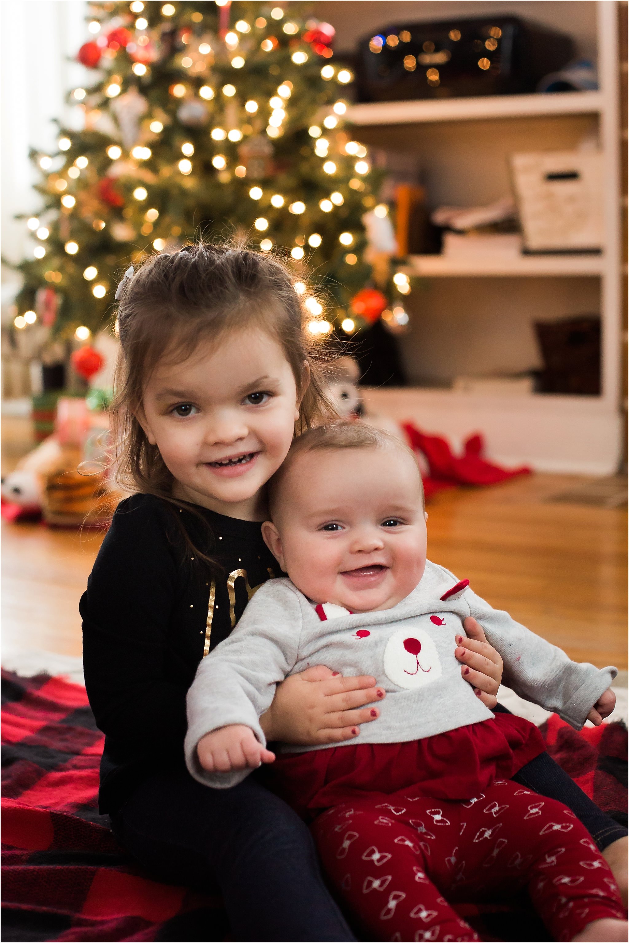 photo of 5 months old girl and toddler sister in front of Christmas tree