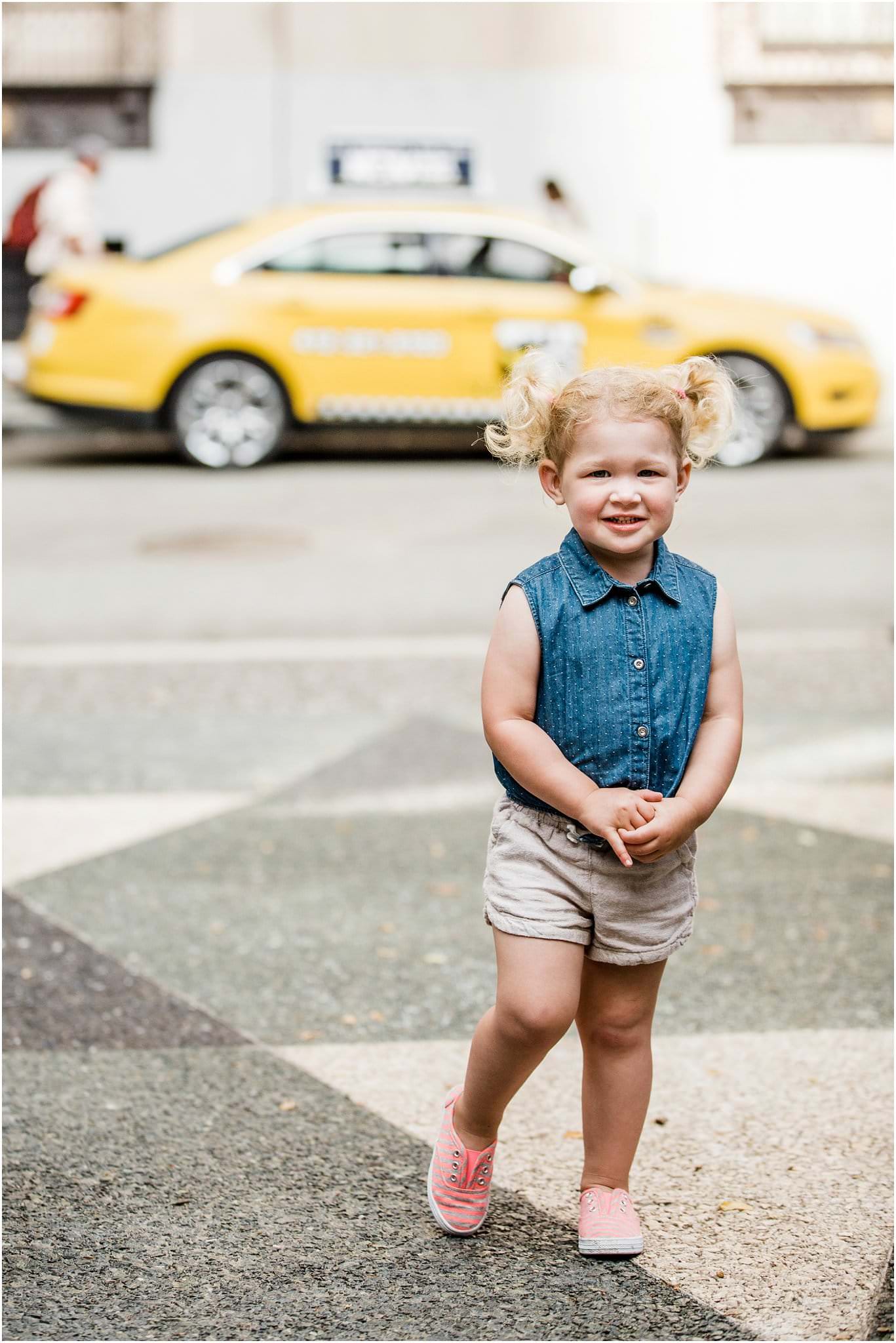 Little girl downtown in front of taxi