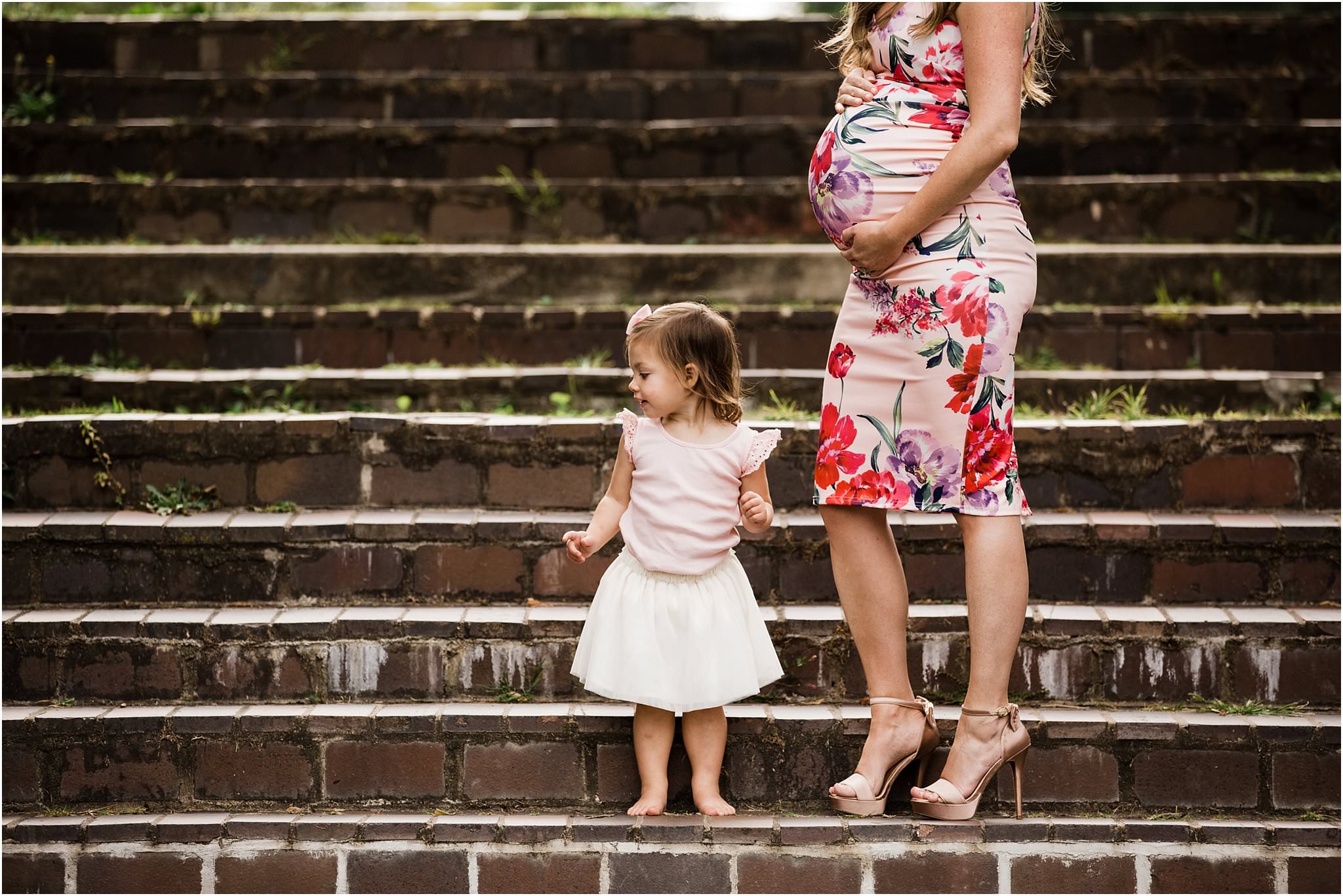 expecting mother in floral dress with toddler daughter