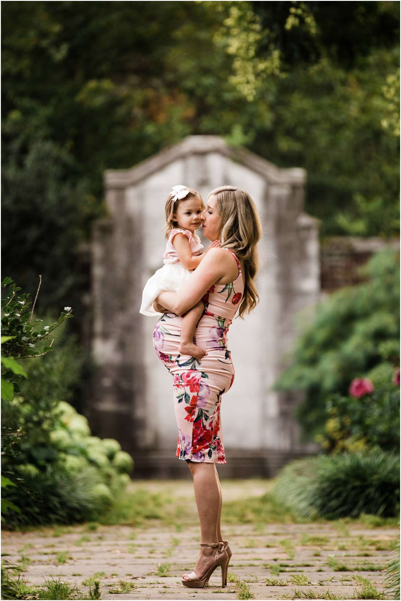 gorgeous mother in form fitting ASOS floral maternity dress holding daughter