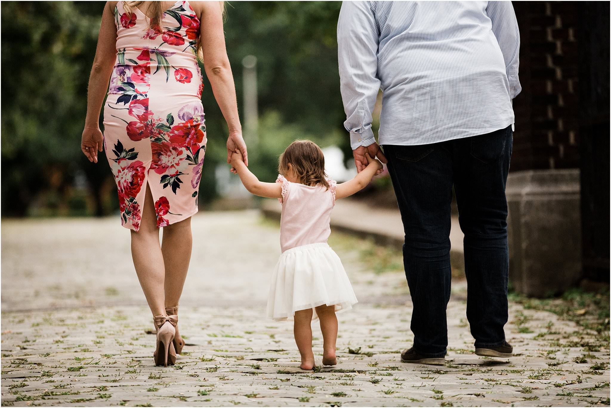 expecting mother and father walking with toddler daughter