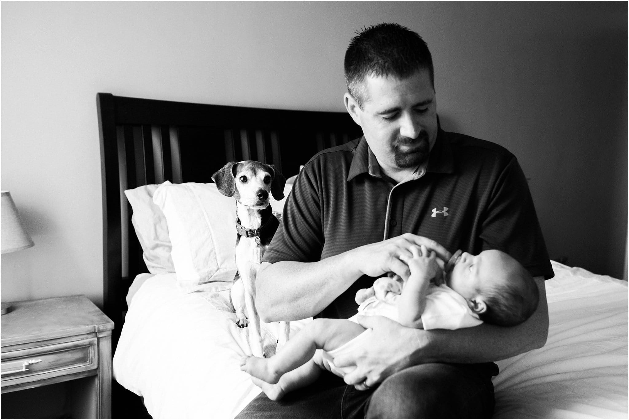 Dog watching father hold new baby boy