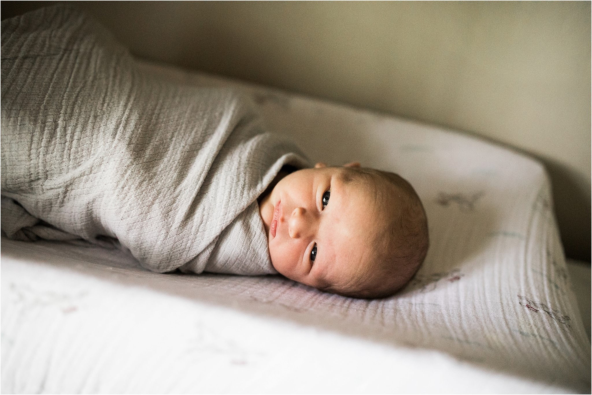 swaddled newborn baby boy in nursery