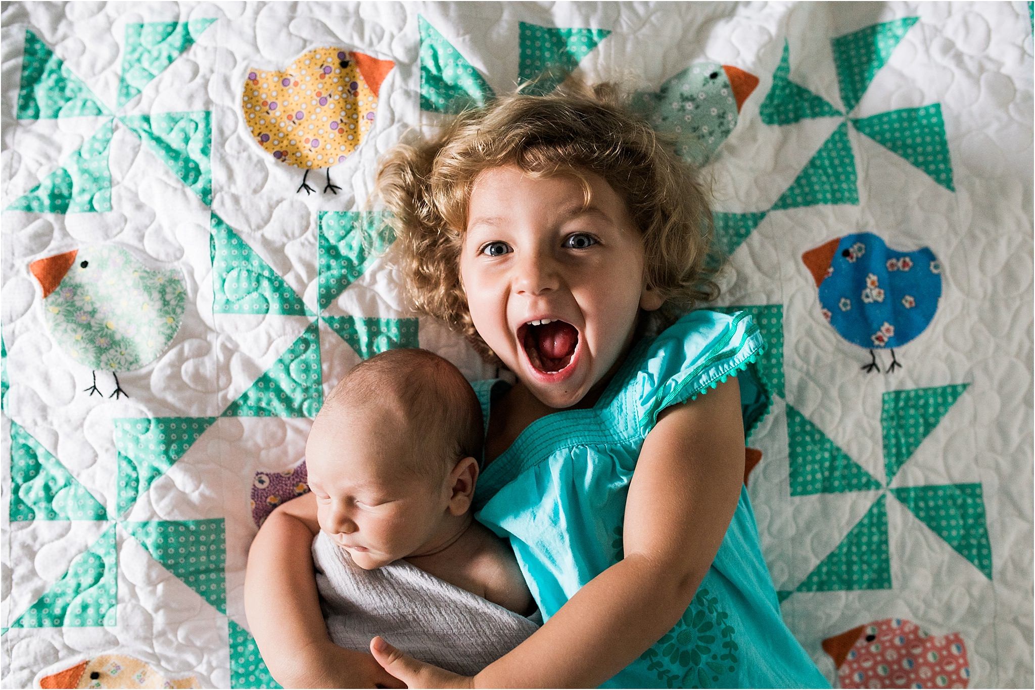 photo of big sister and new baby brother on family quilt