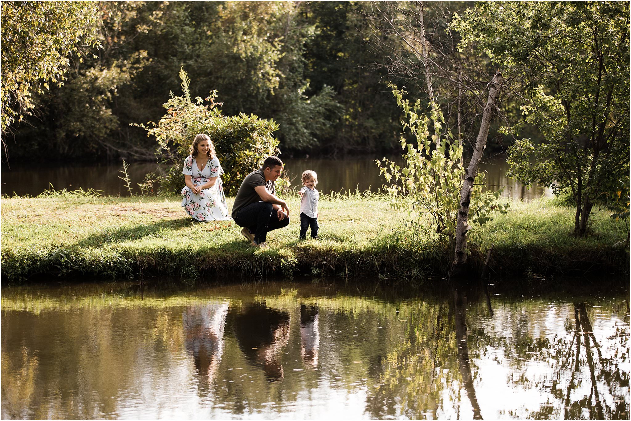 mother watching father and son near lake