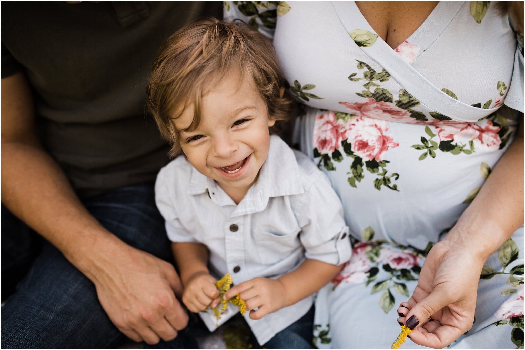 toddler boy laughing and sitting with parents