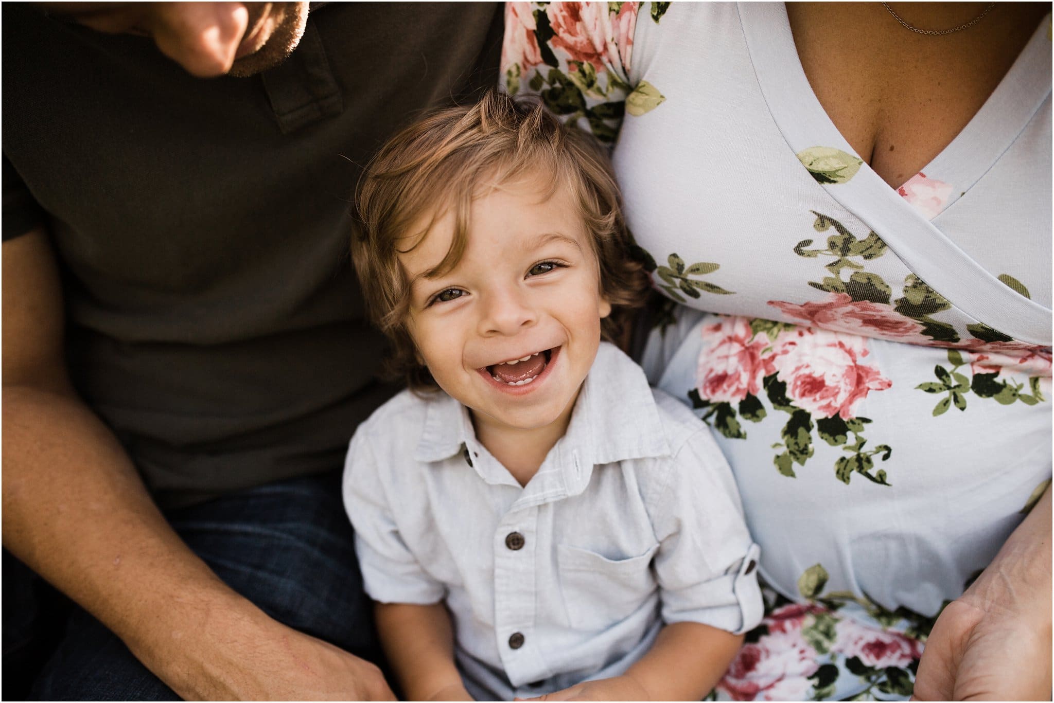 toddler boy smiling and sitting with parents