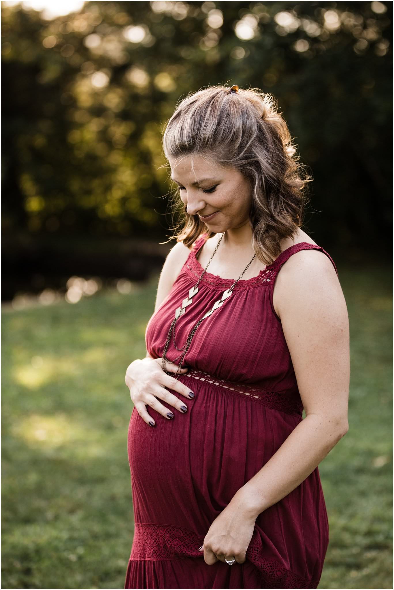 expecting mother in maroon maternity gown at golden hour