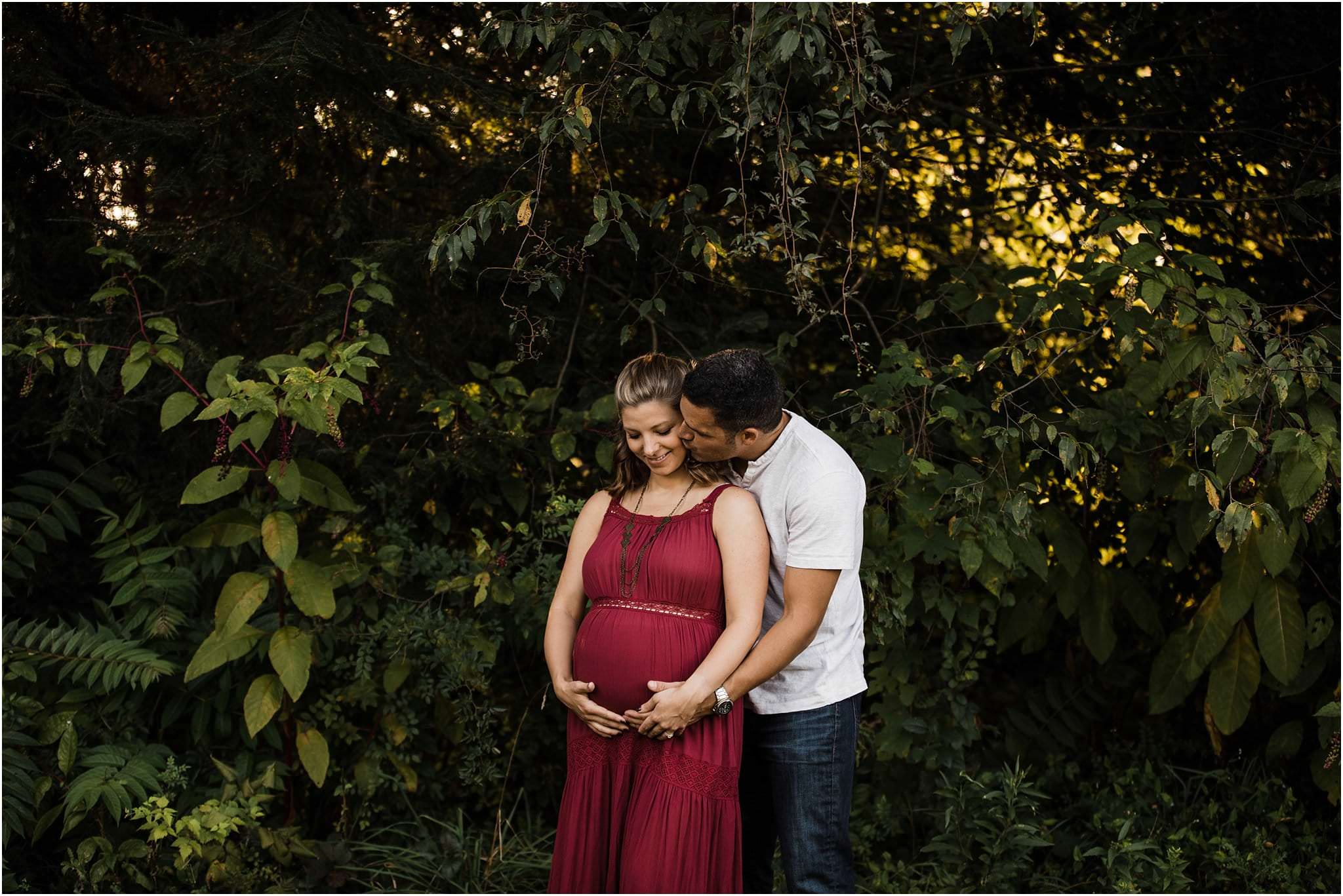 dad kissing expecting mother and holding belly