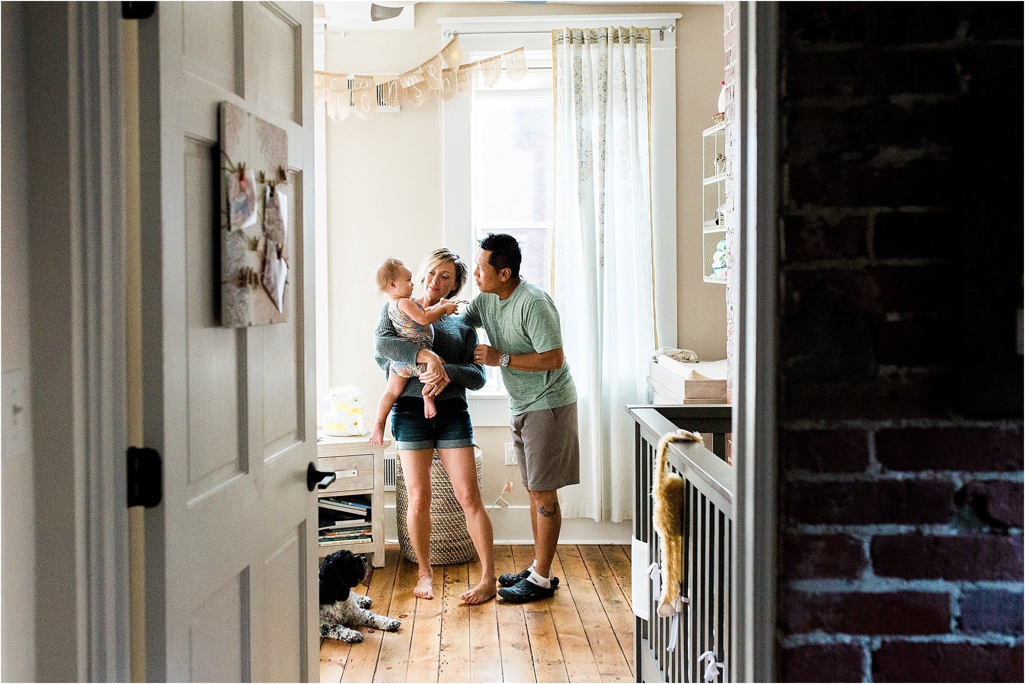 looking through doorway at parents holding baby girl in nursery