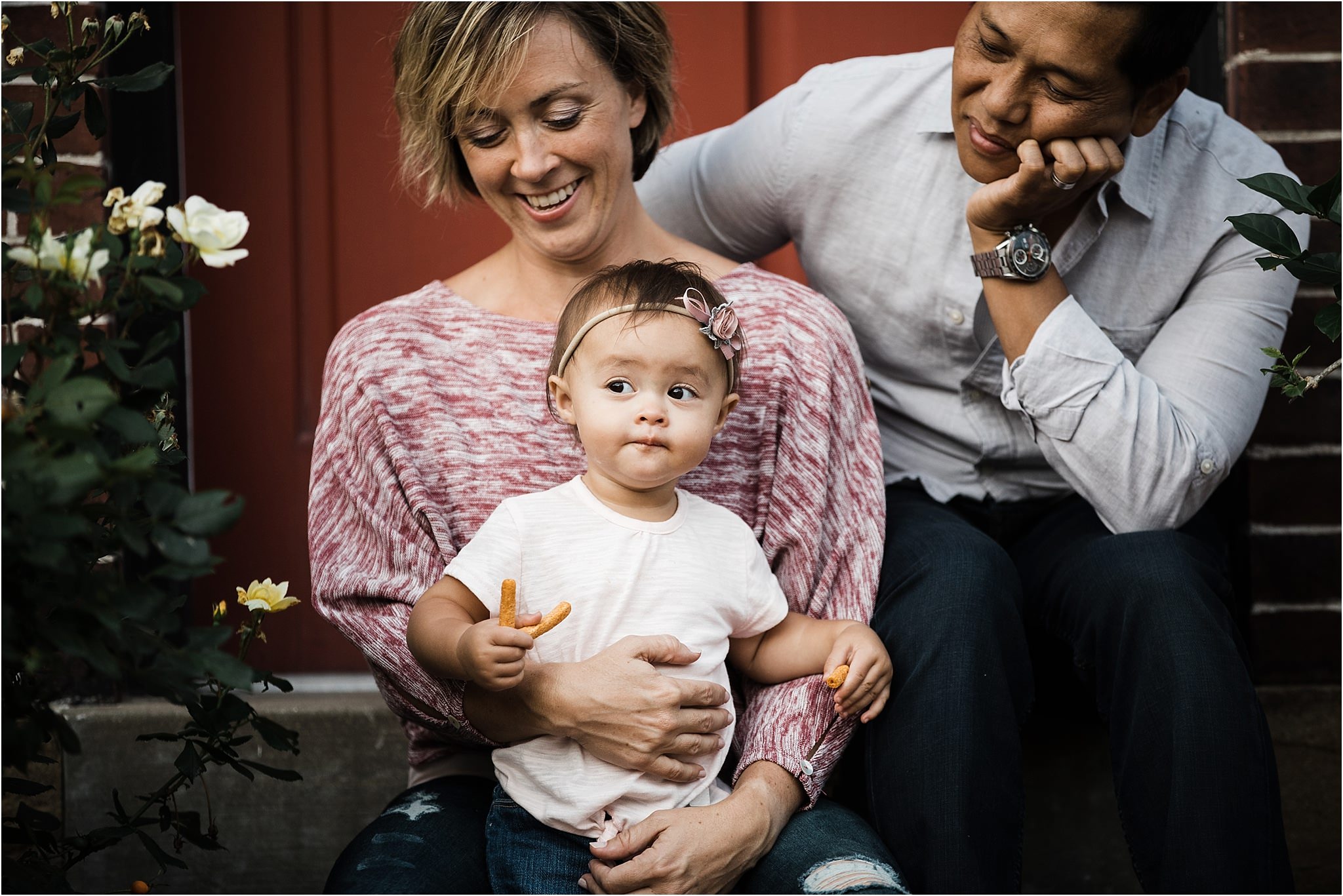 parents holding daughter on stoop