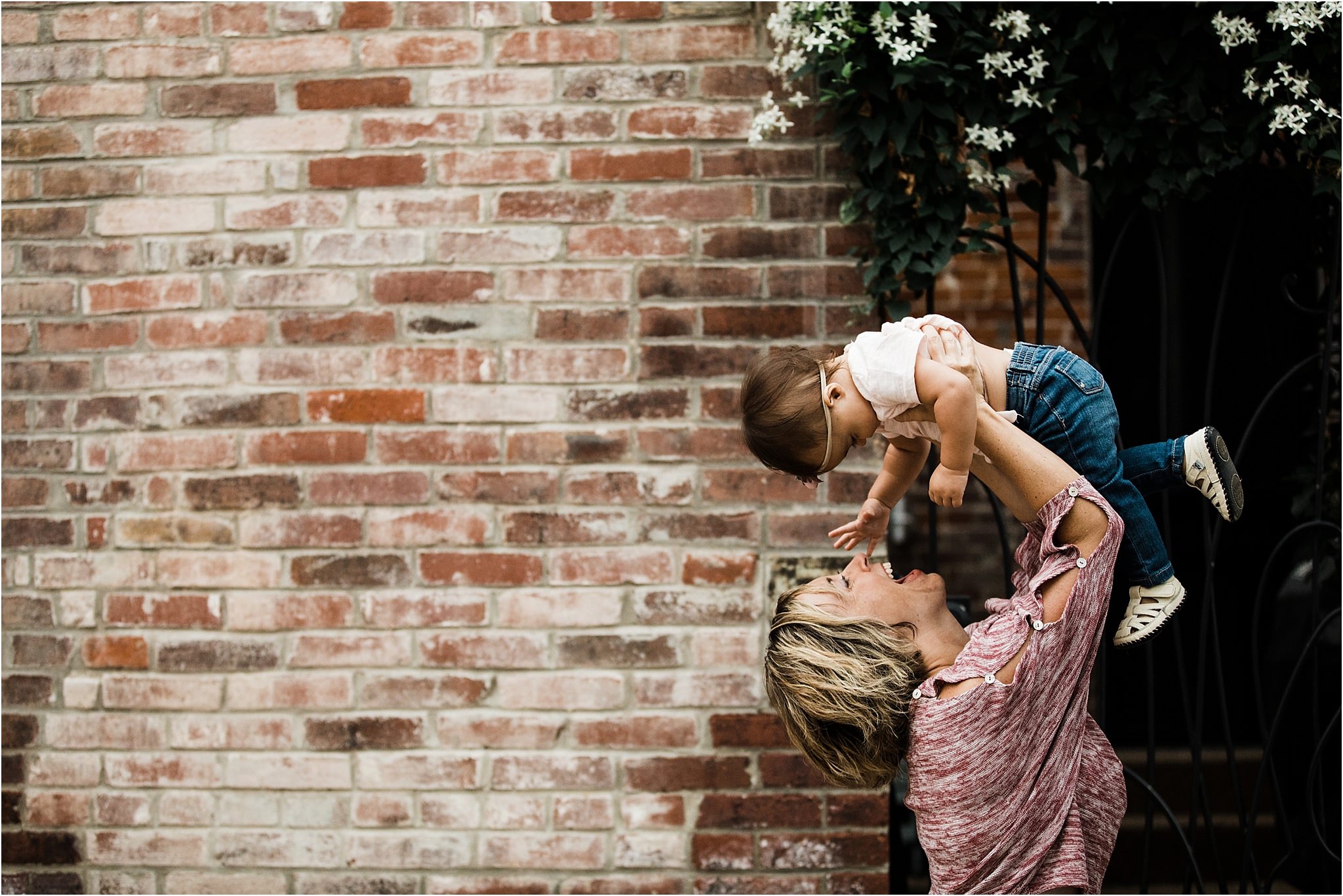 mother laughing and holding daughter in the air