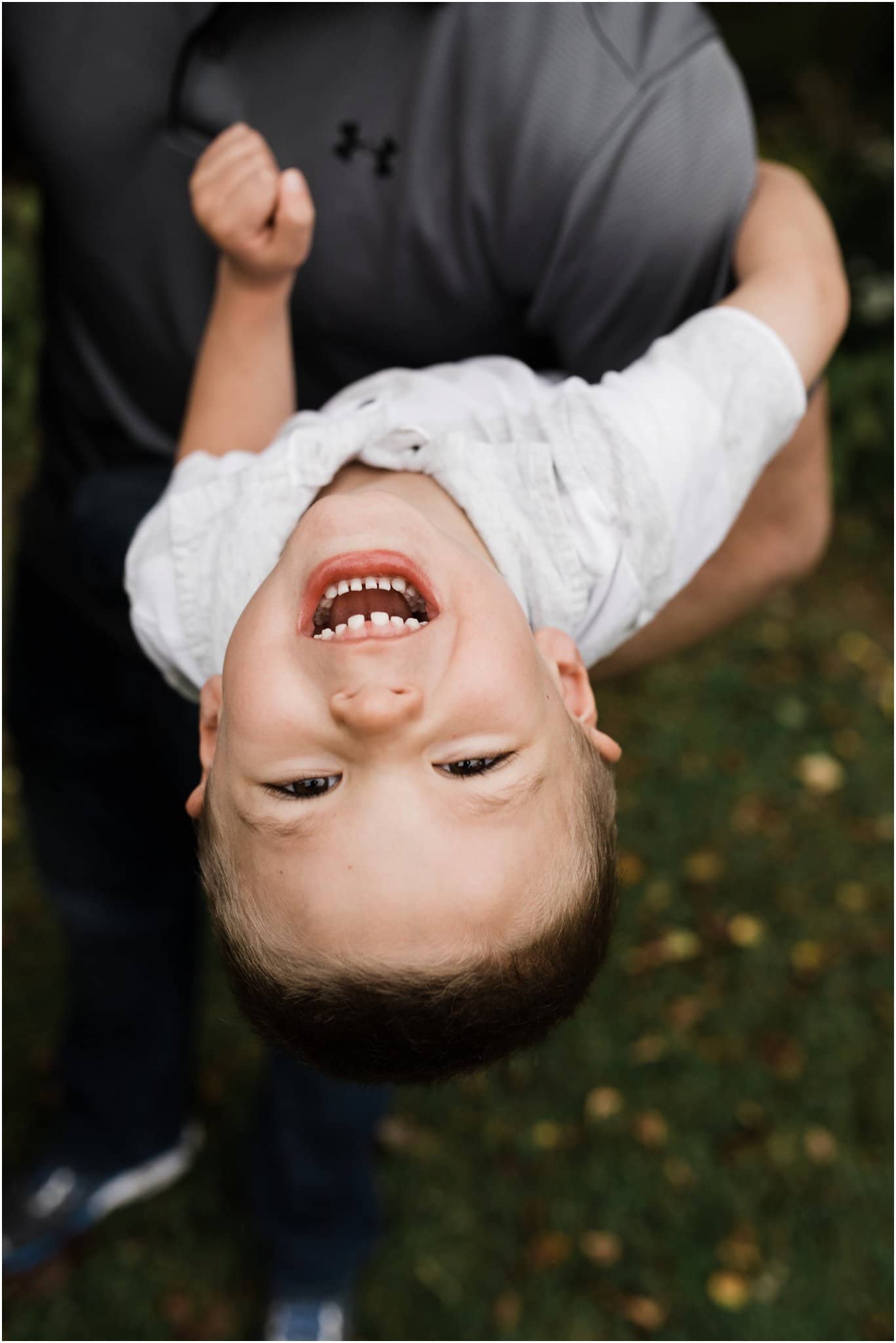 toddler boy swinging upside down from fathers arms