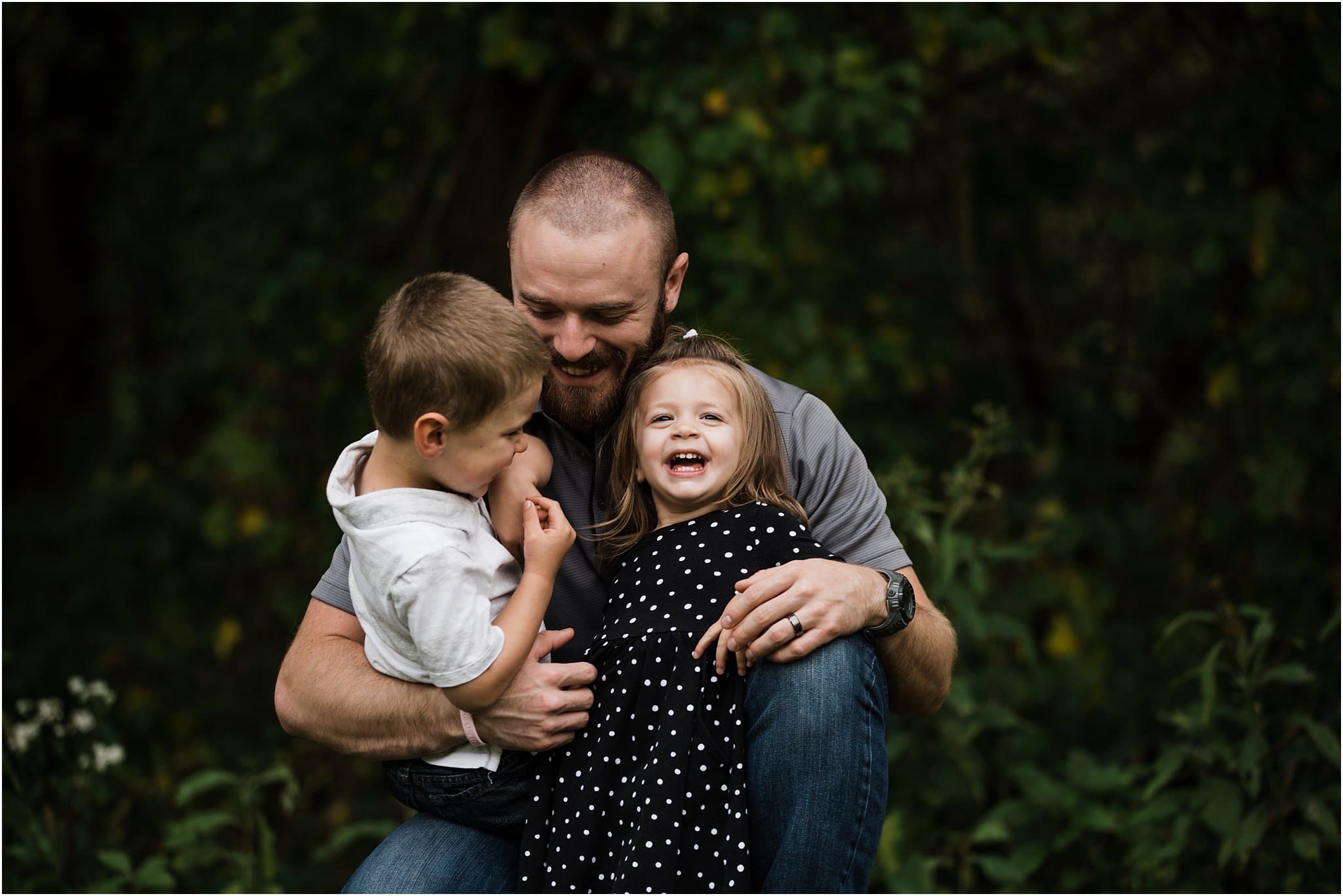 father laughing and holding children