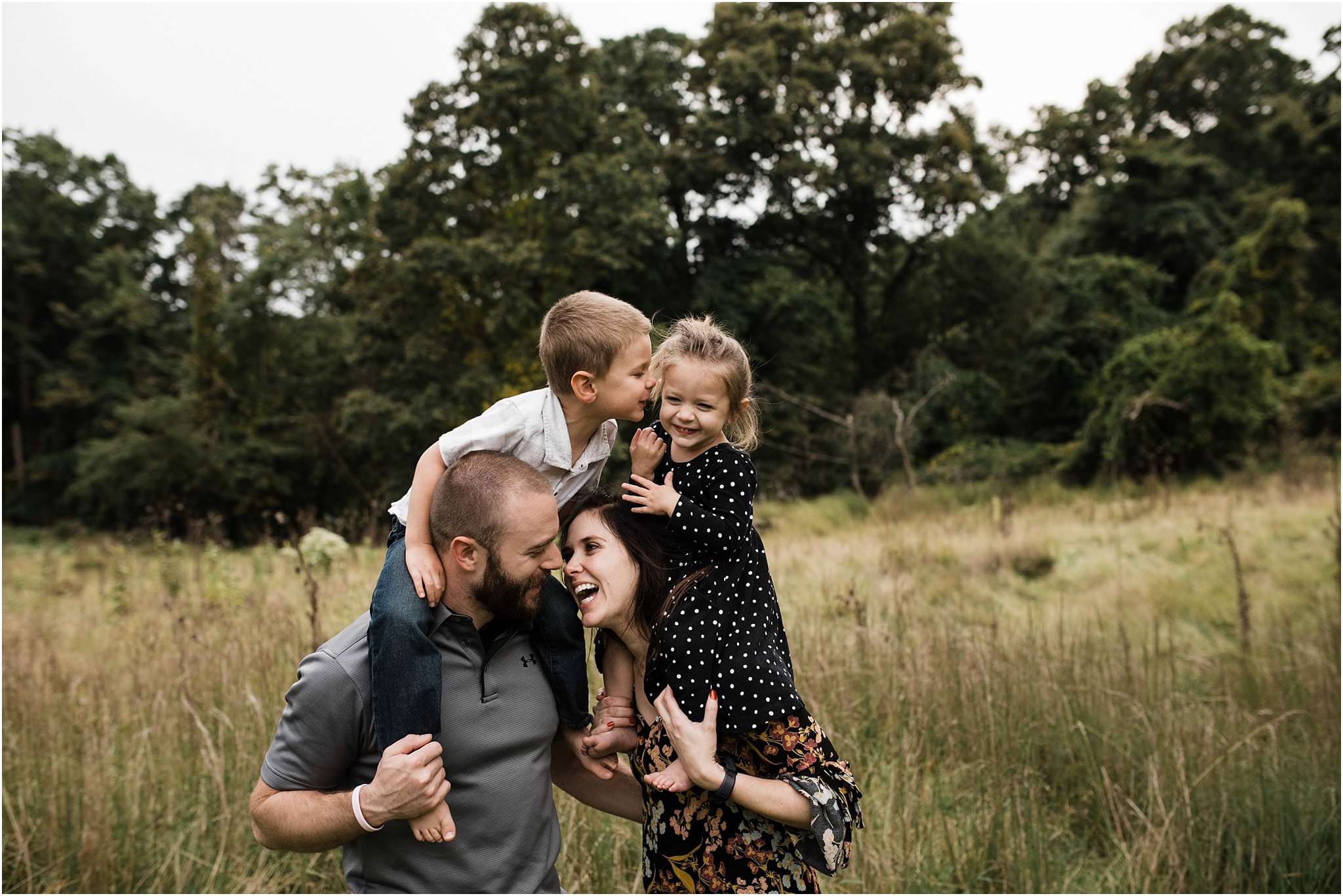 sibling kiss on parents shoulders