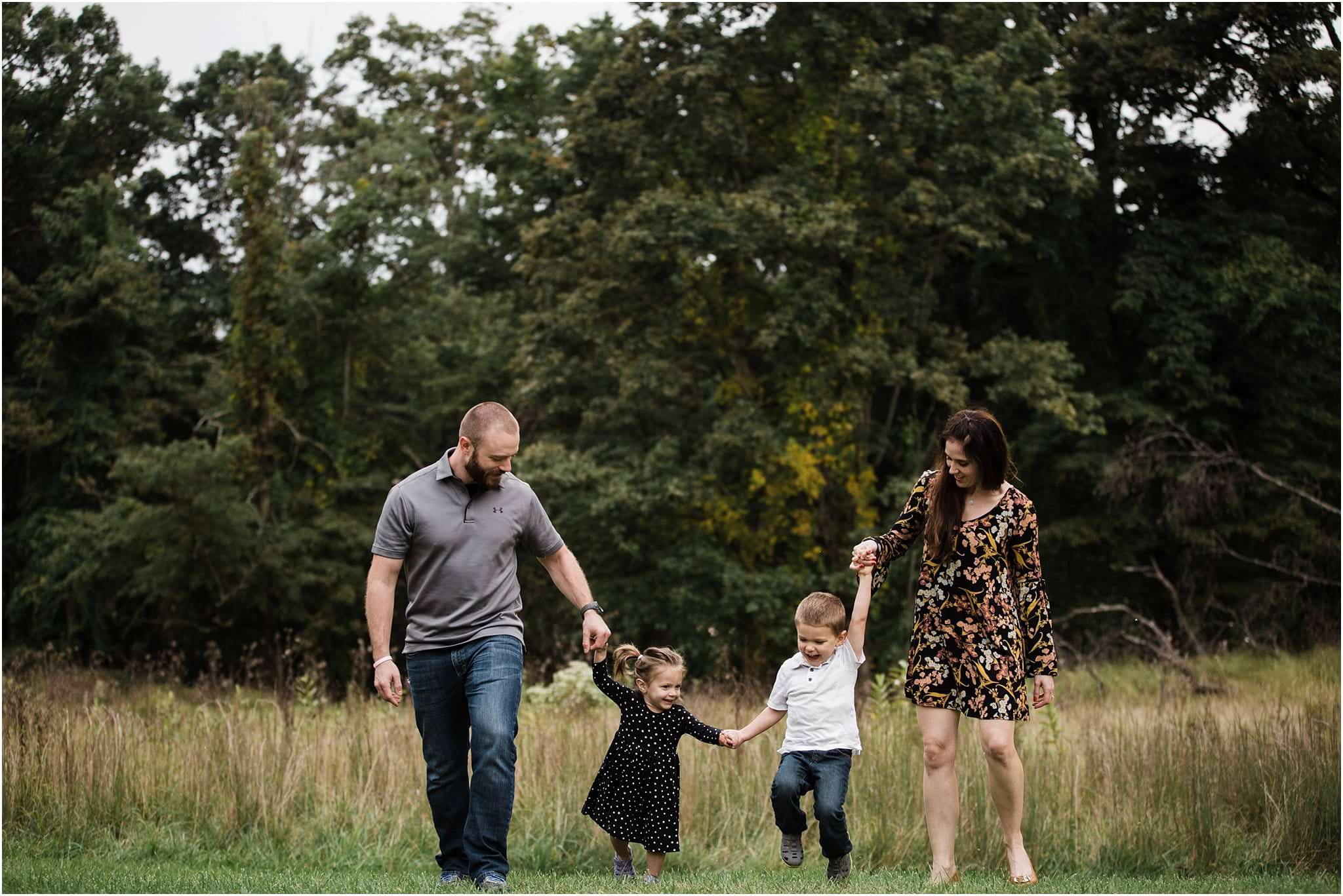 Family holding hands and walking in a field