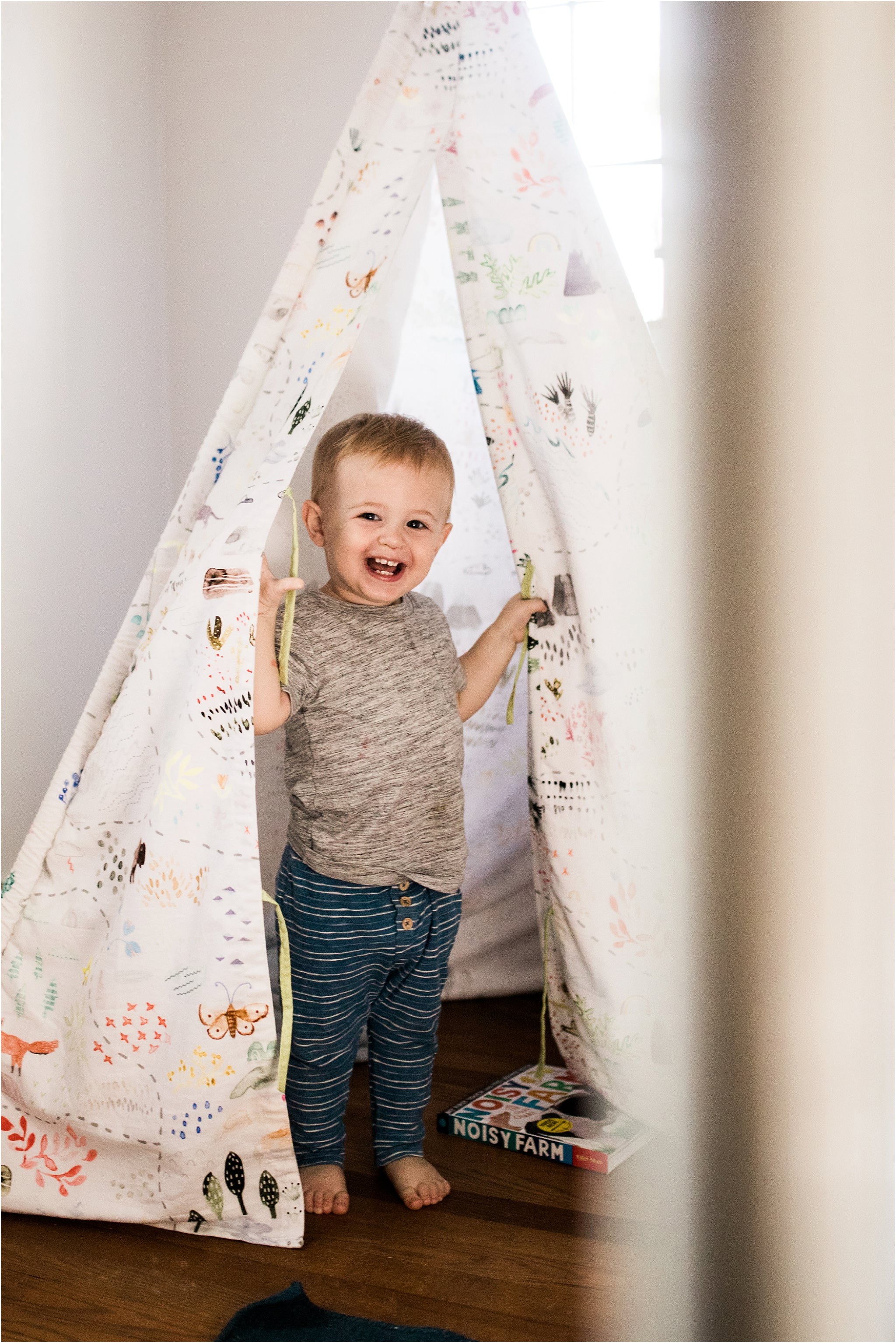 one year old boy playing in teepee