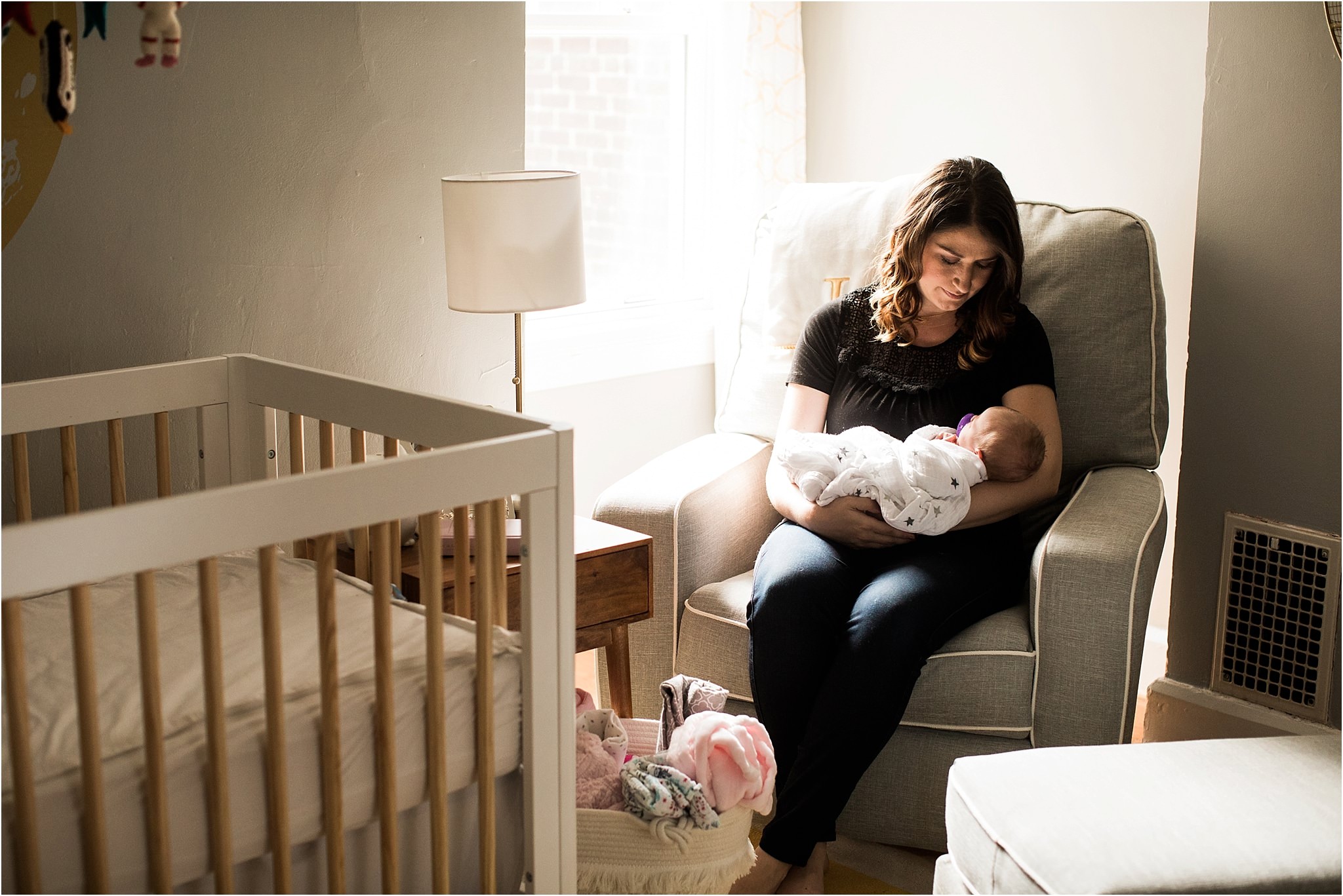 mother rocking newborn baby in nursery