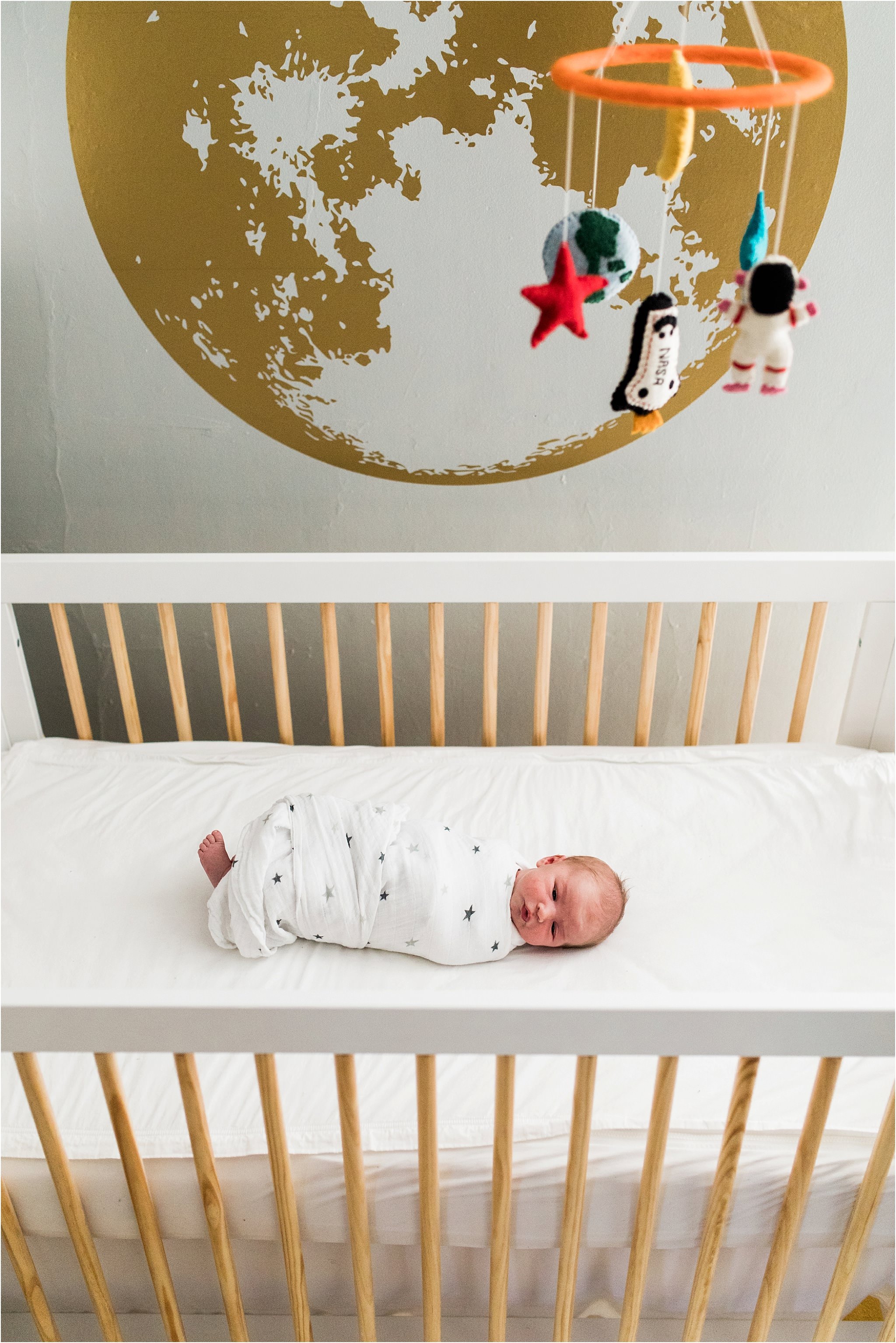 photos of newborn in crib with moon wall decal