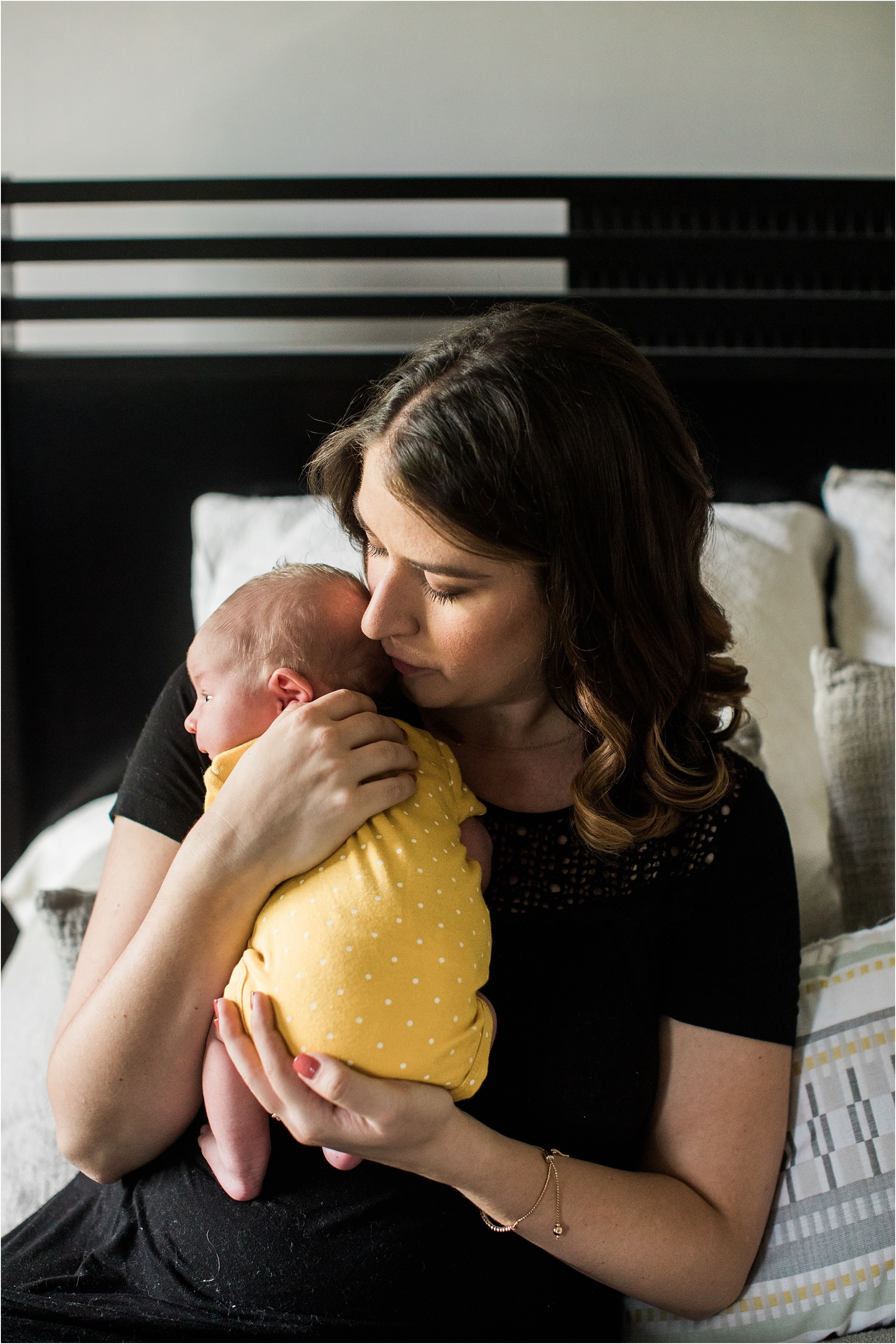 mother holding newborn baby girl in yellow onesie