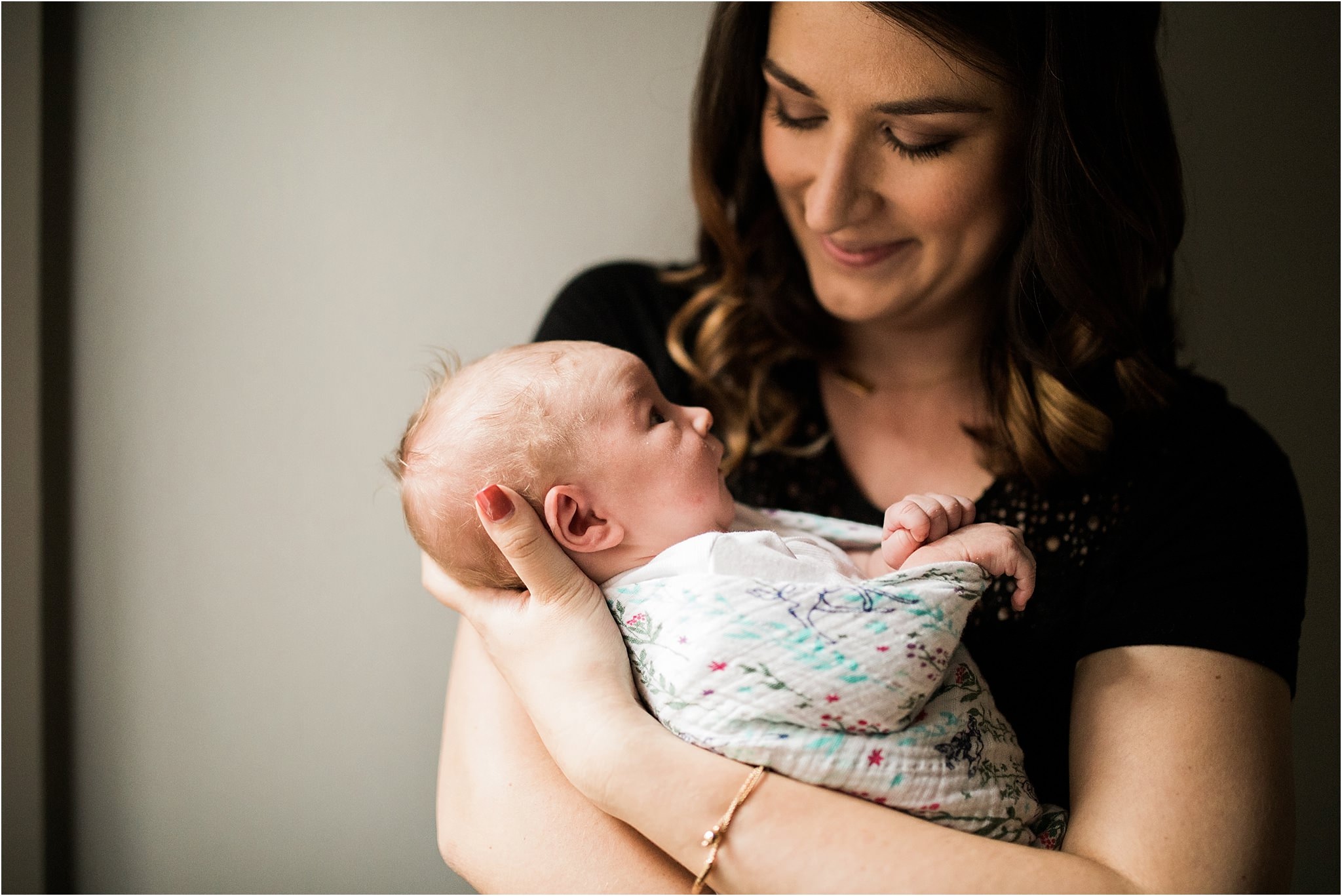 new mom holding and smiling at newborn during in home photo session