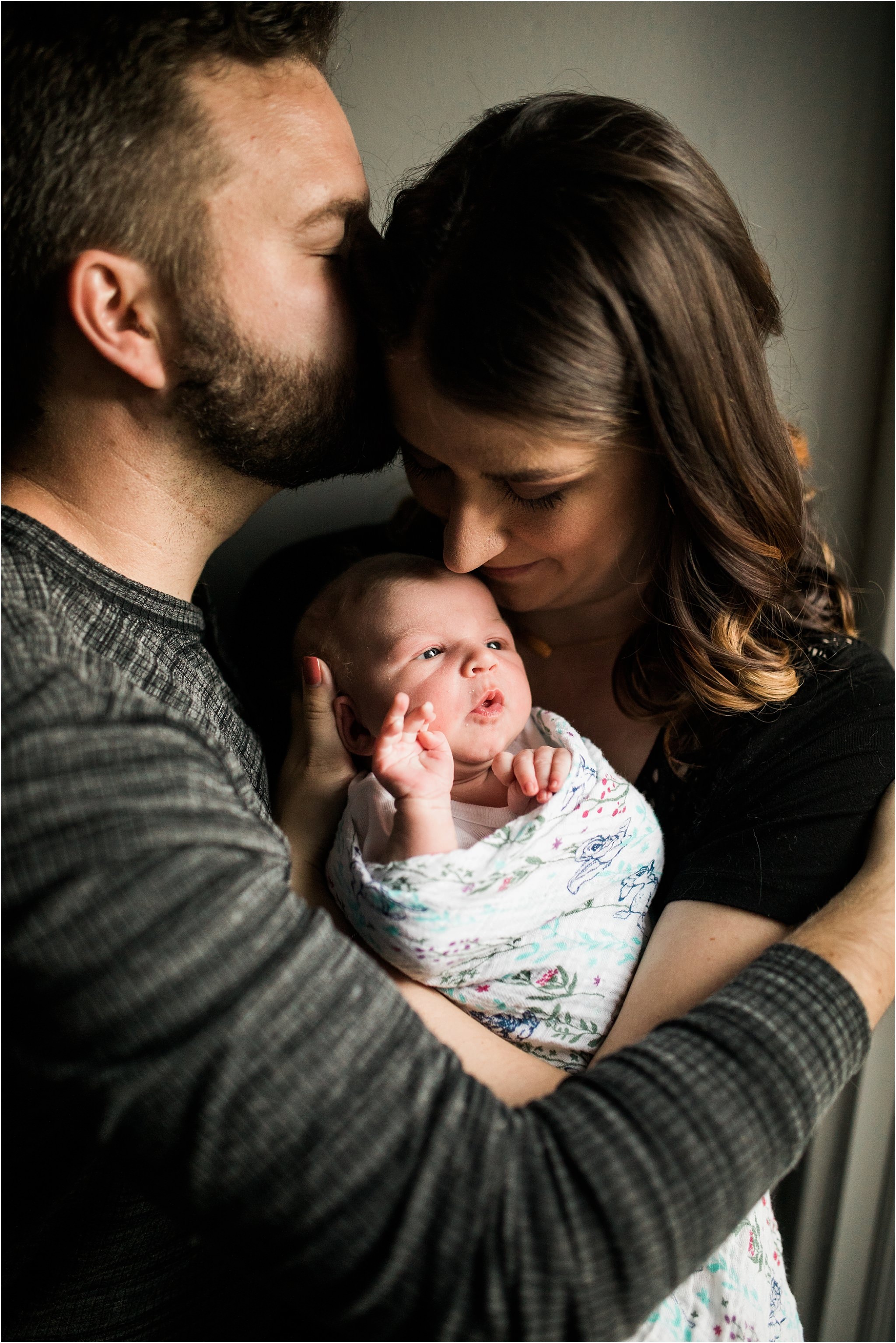 new parents snuggling brand new baby girl