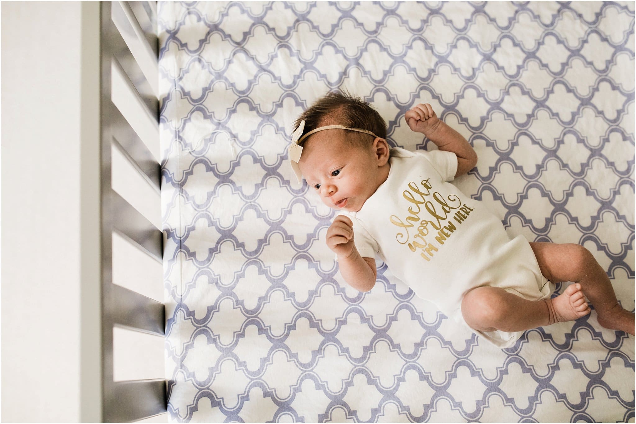 photo of newborn in crib wearing hello world I'm new here onesie