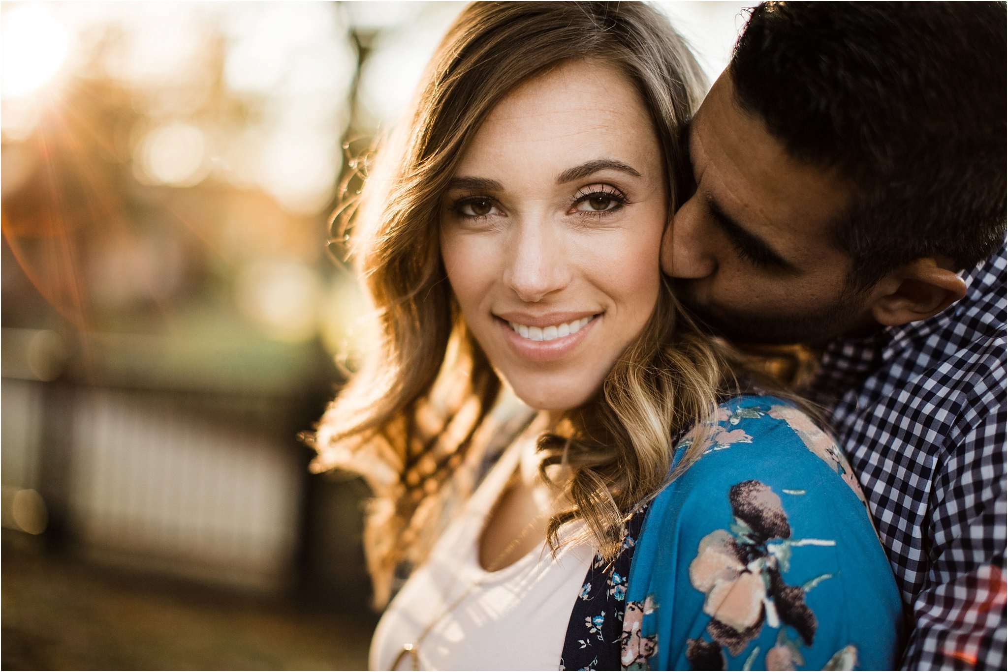 Husband kissing pregnant wife at golden hour