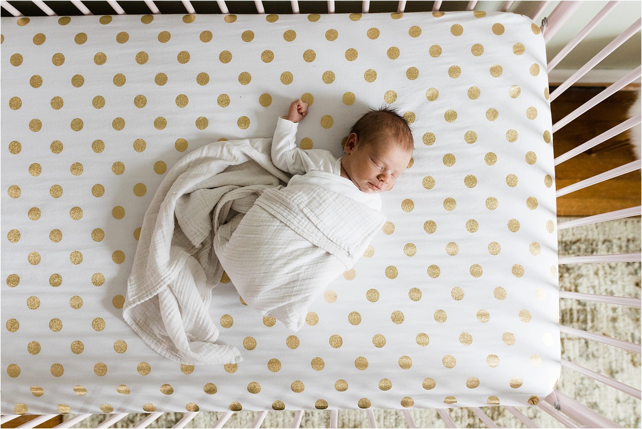 newborn sleeping in pink crib with gold polka dot sheets