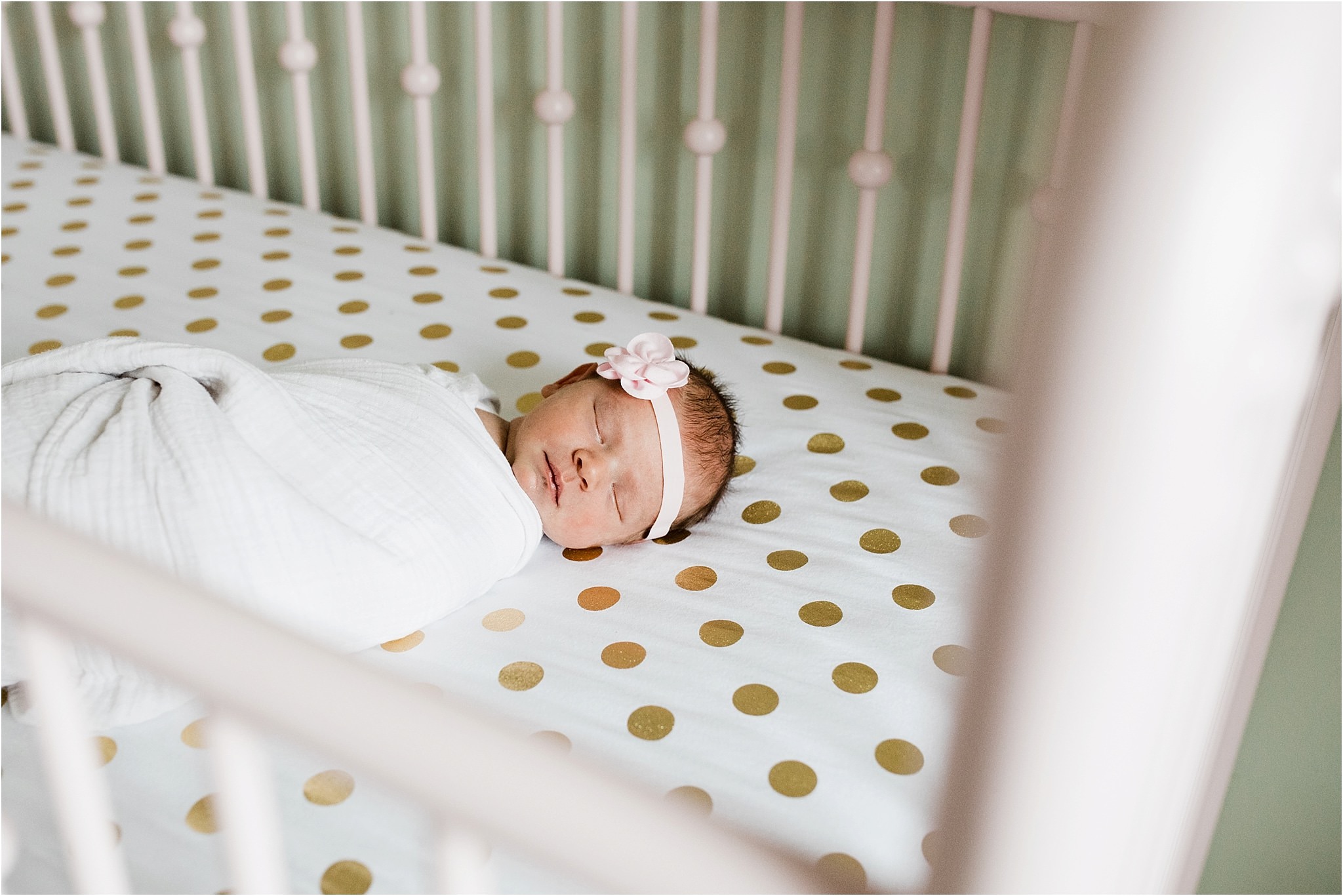 newborn sleeping in pink crib with gold polka dot sheets