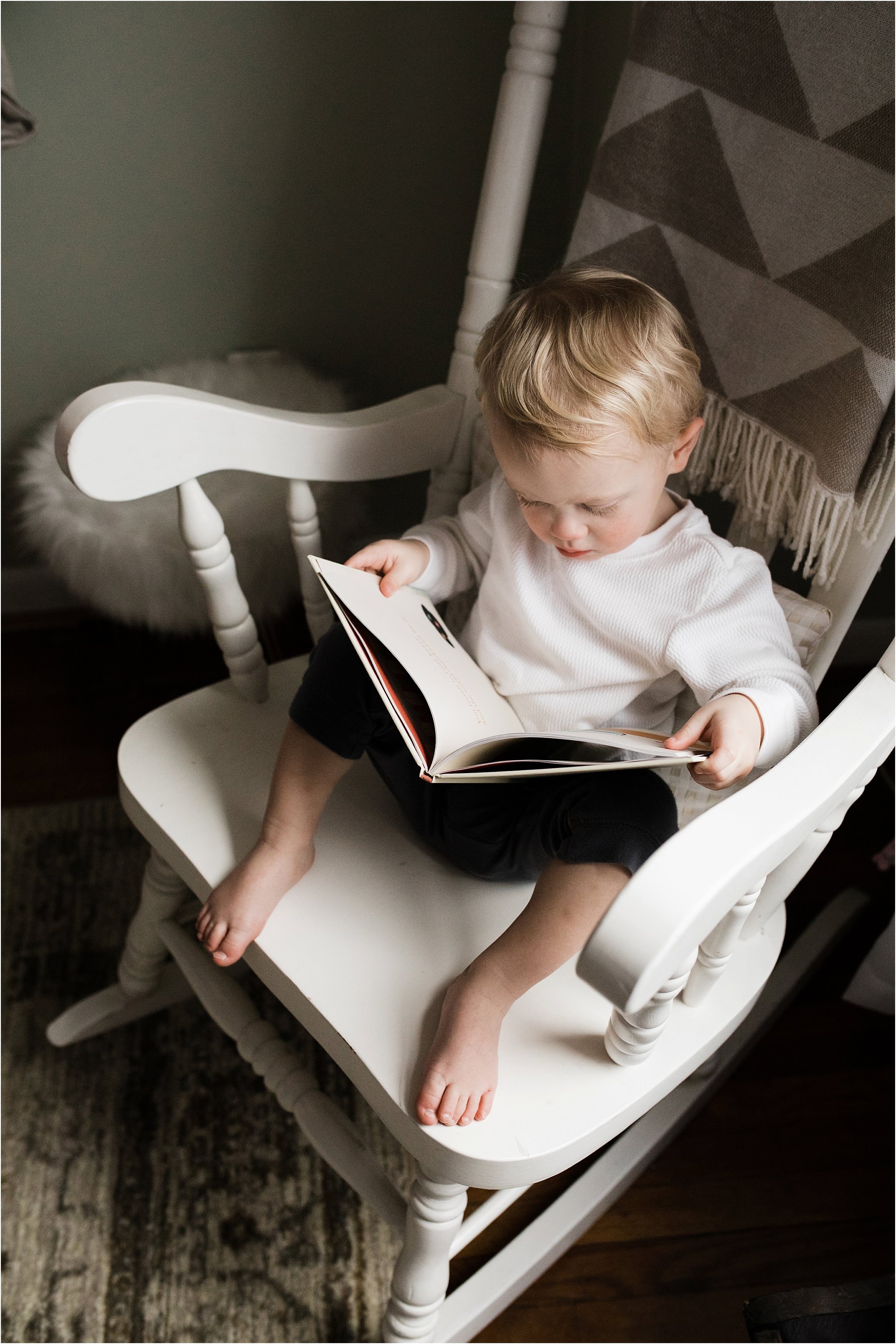 toddler boy reading in sisters nursery