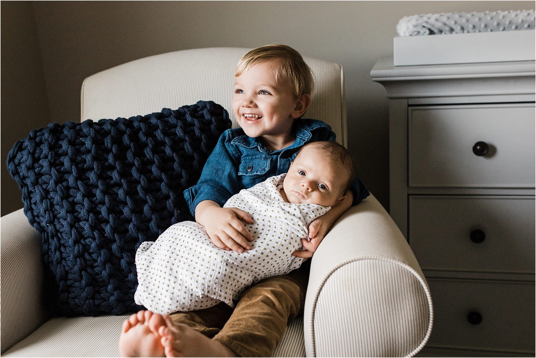 big brother holding and loving new baby brother in home nursery