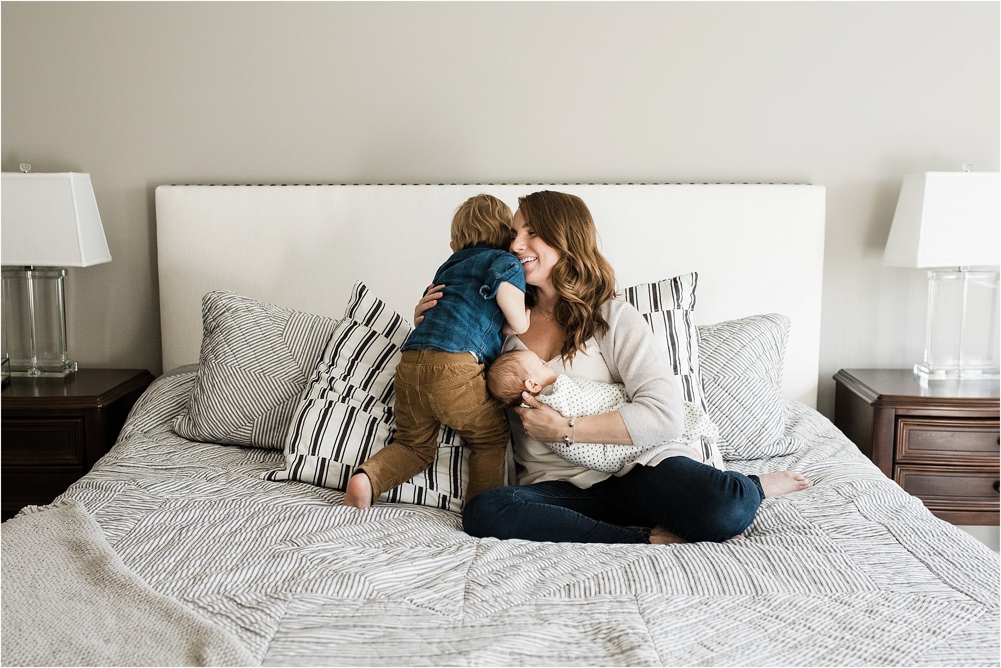 toddler kissing mother holding new brother