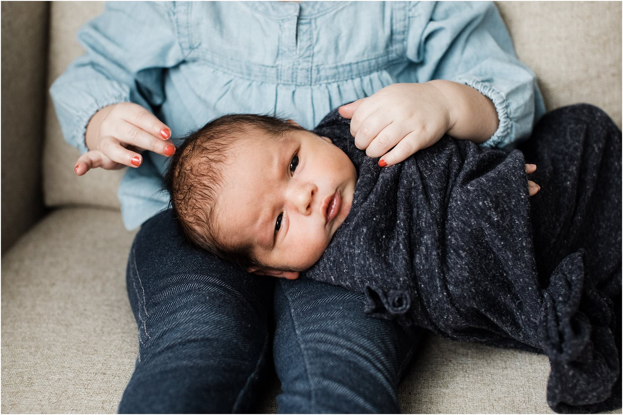 newborn being held by big sister