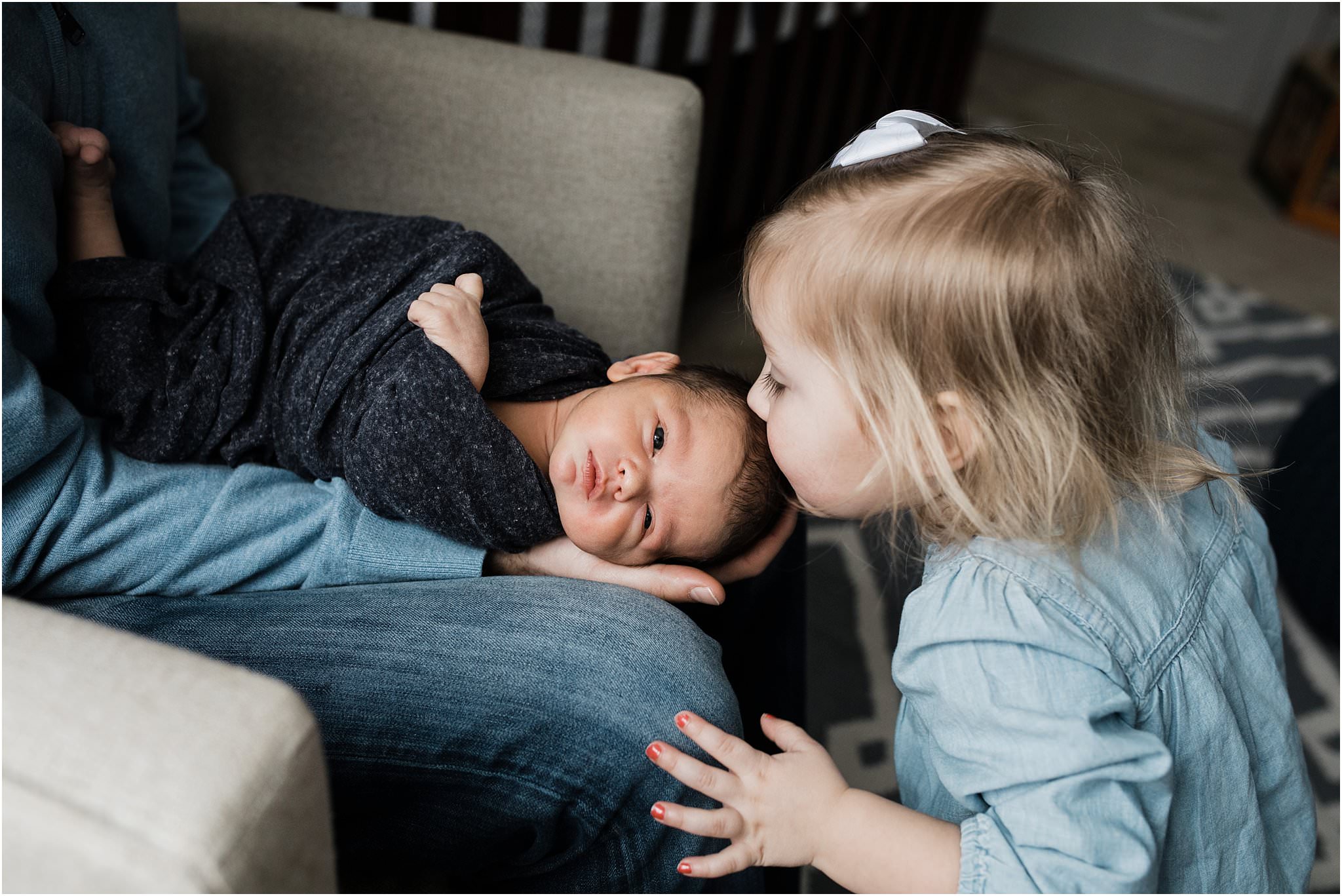 big sister kissing newborn brother