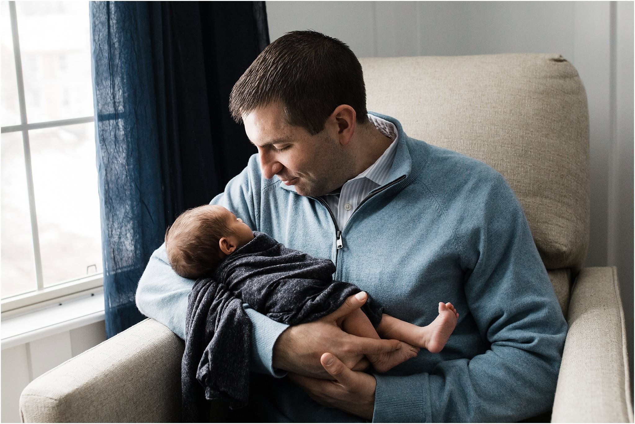 father holding newborn son in nursery