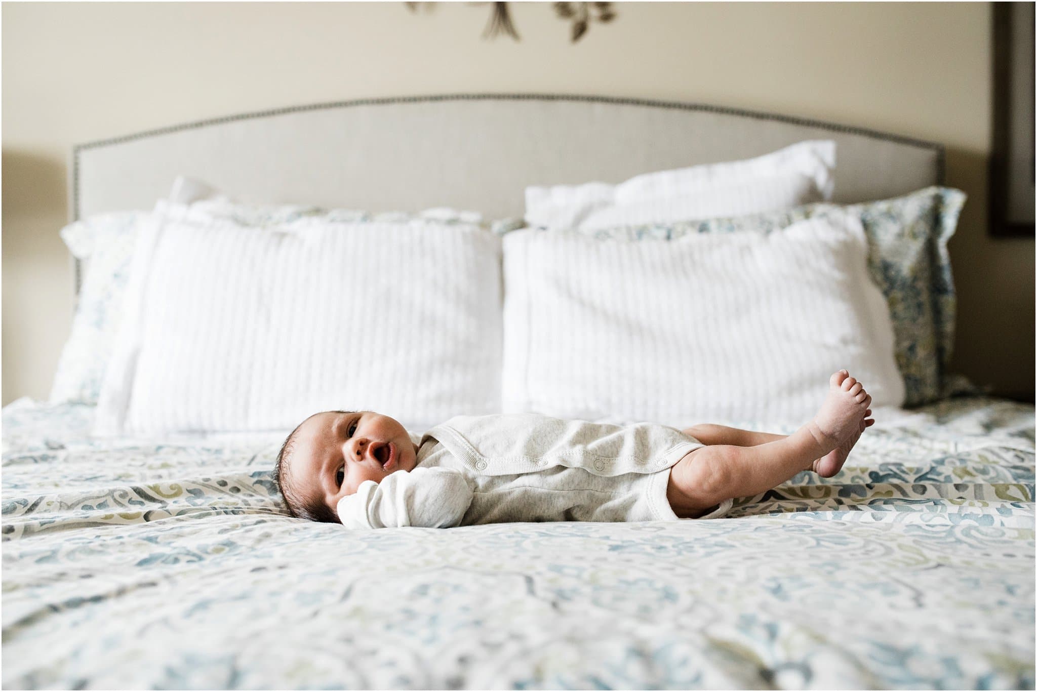 newborn in white onesie on bed